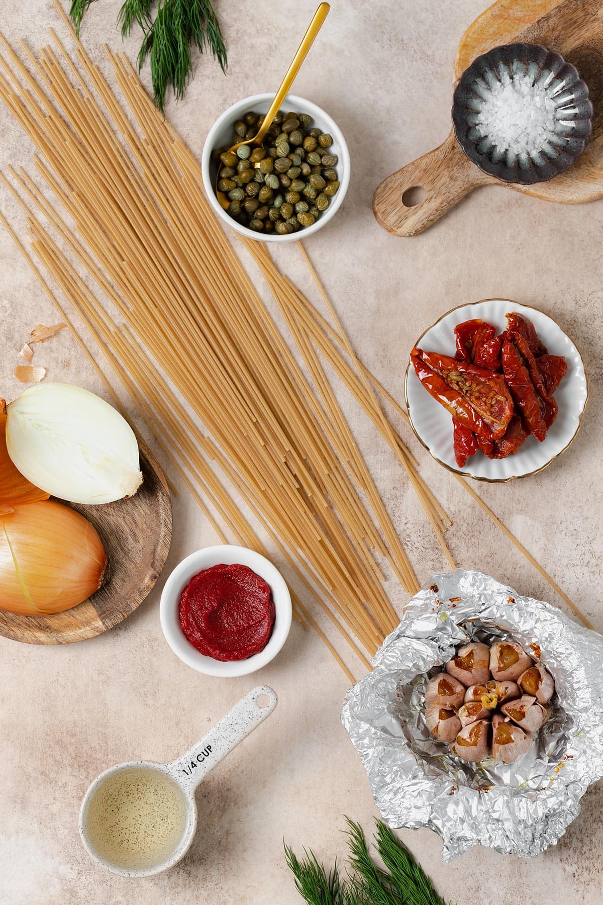Ingredients for creamy sun-dried tomato pasta shown laid out on a beige background.