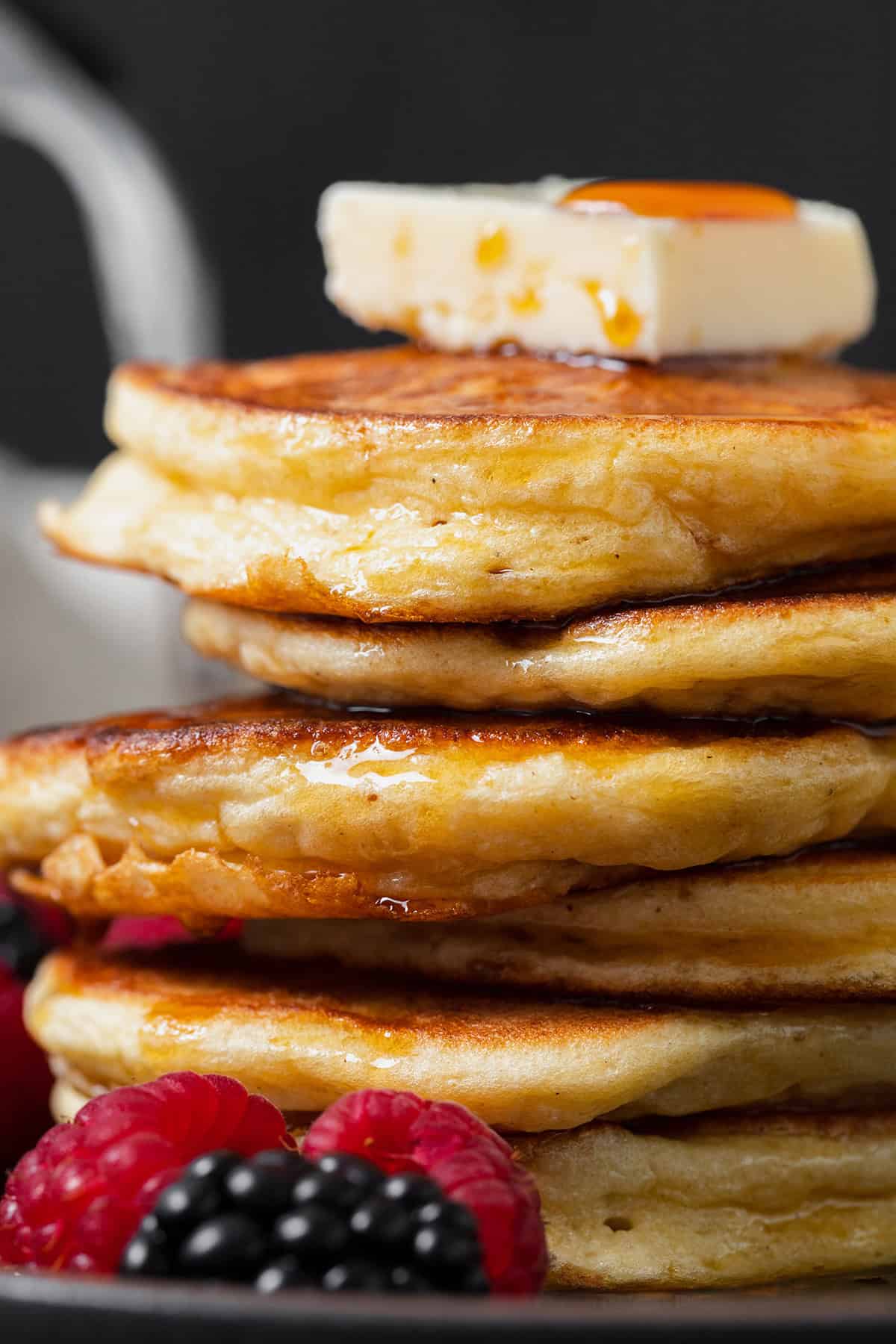 A close up of greek yogurt pancakes with maple syrup and butter.