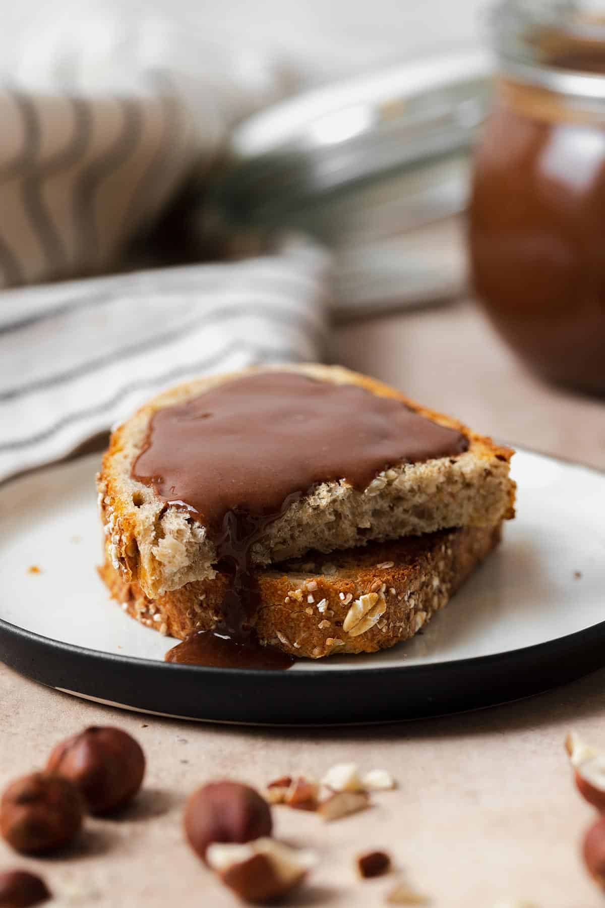 Healthy Vegan Nutella spread on toasted bread. On a white plate and beige background.