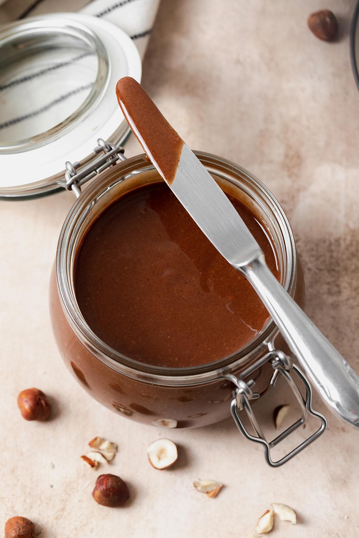 Homemade Nutella in a glass jar with a butterknife resting on the top.