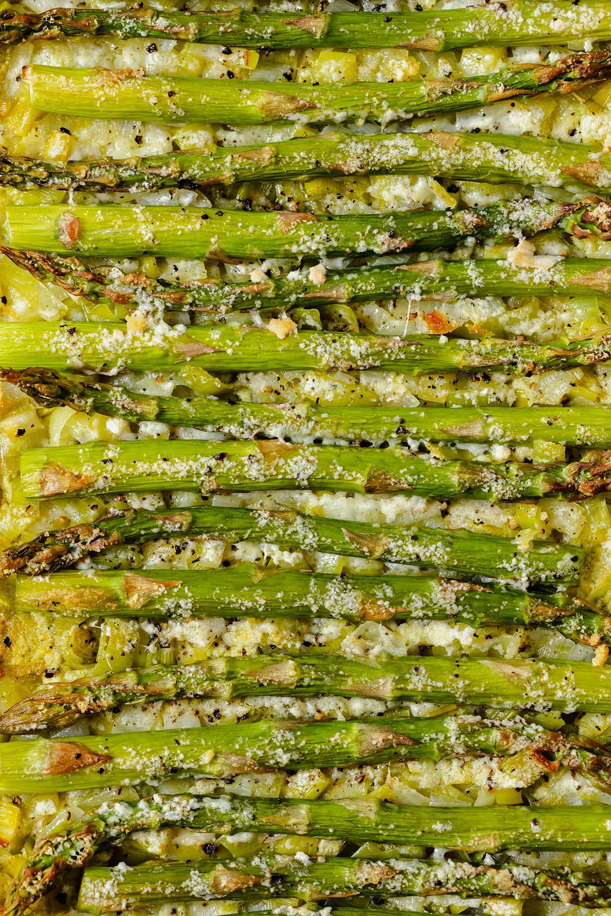 A close up of just the filling of the tart. Asparagus, goat cheese pesto spread, pecorino cheese with golden bits from baking.