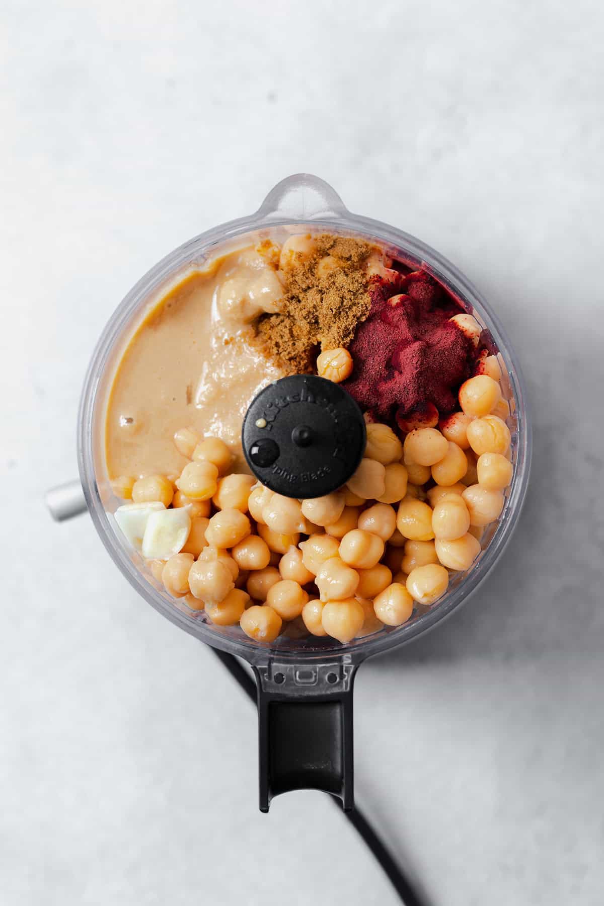 A photo of a small food processor filled with ingredients for the beetroot hummus.