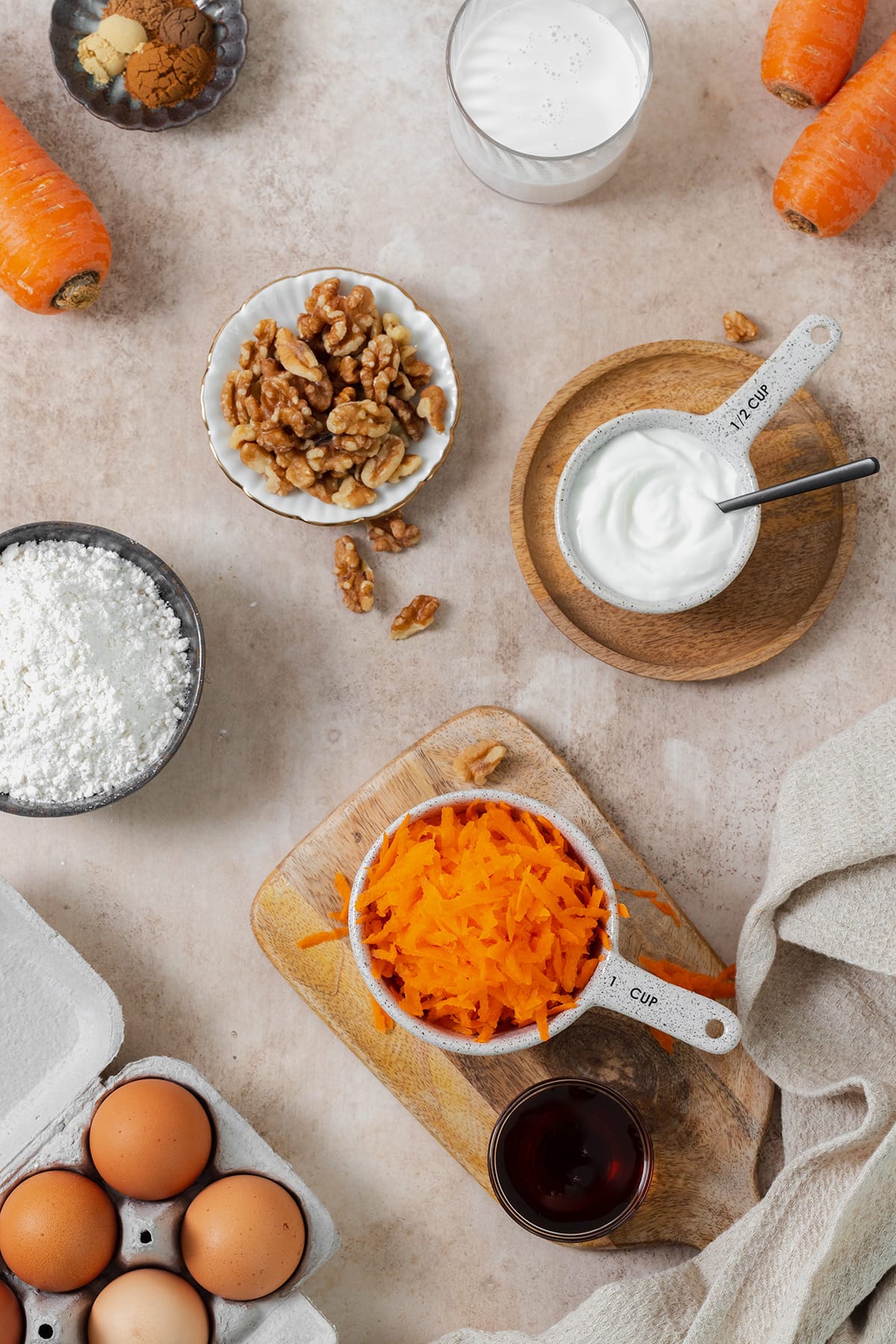 Ingredients for gluten-free carrot cake laid out on a beige background.