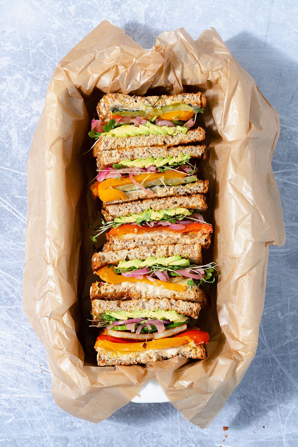 Halloumi sandwiches cut in half and arranged cut side up in a baking dish lined with parchment paper.