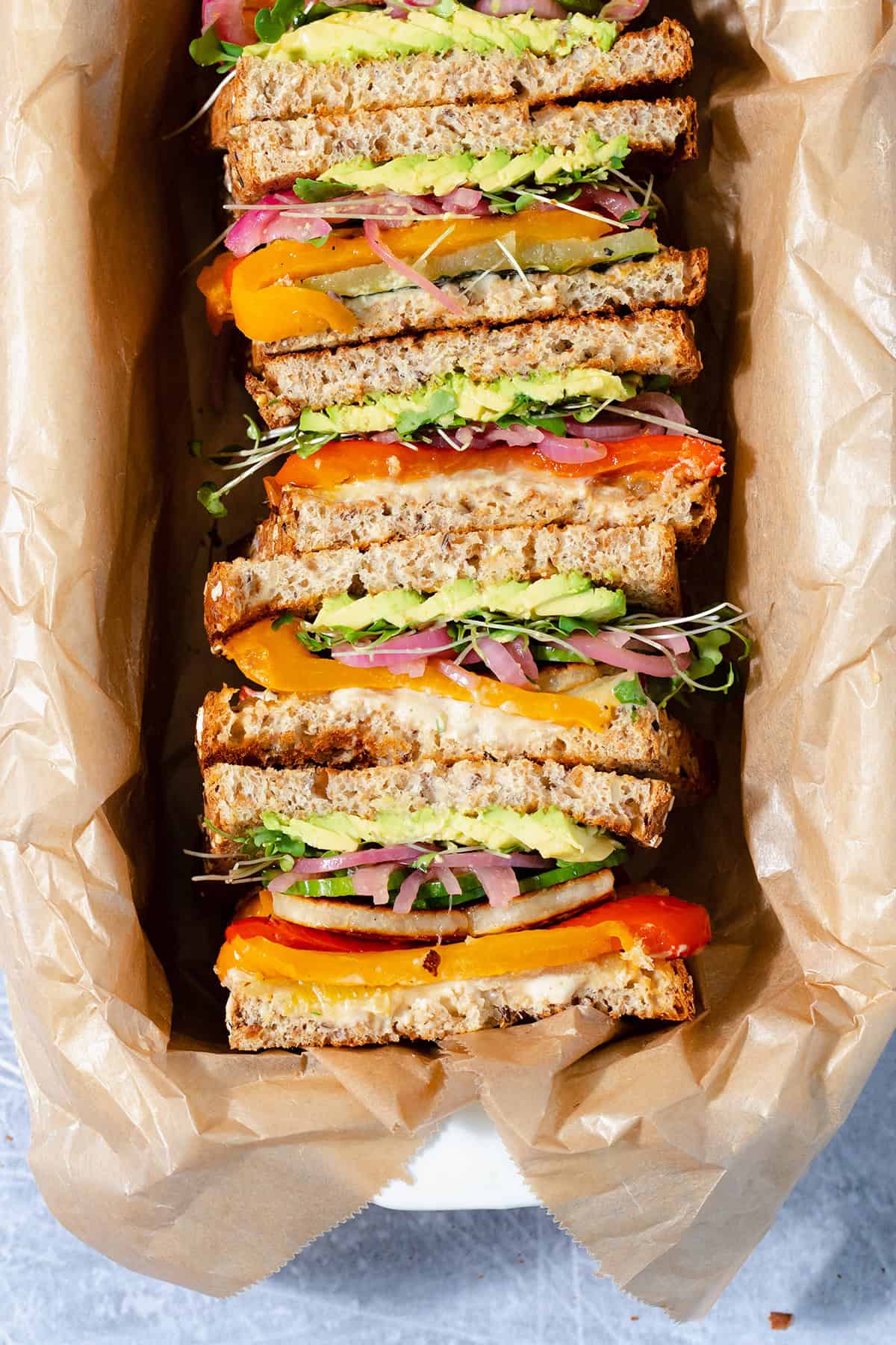 Halloumi sandwiches cut in half and arranged cut side up in a baking dish lined with parchment paper.