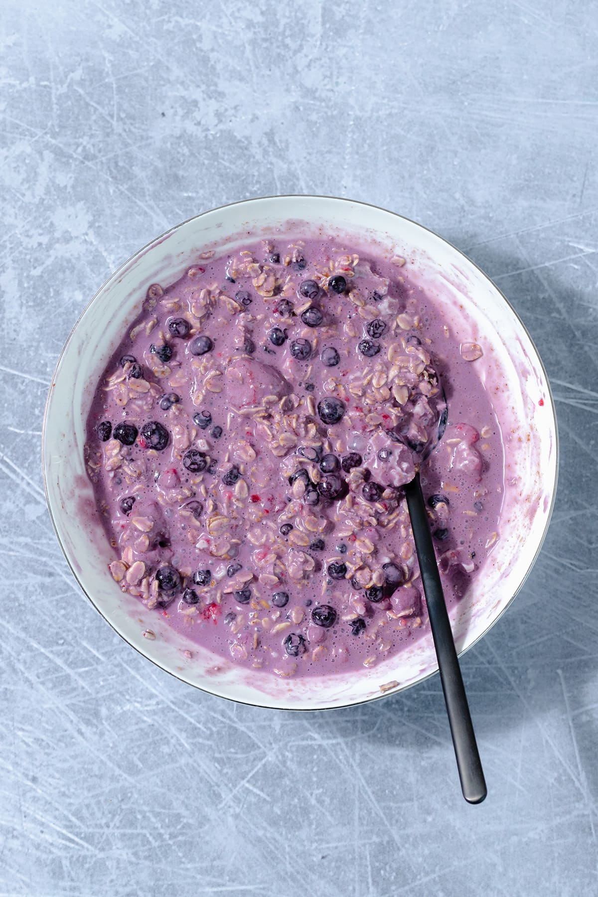 White bowl with all the ingredients for blueberry oats mixed up.