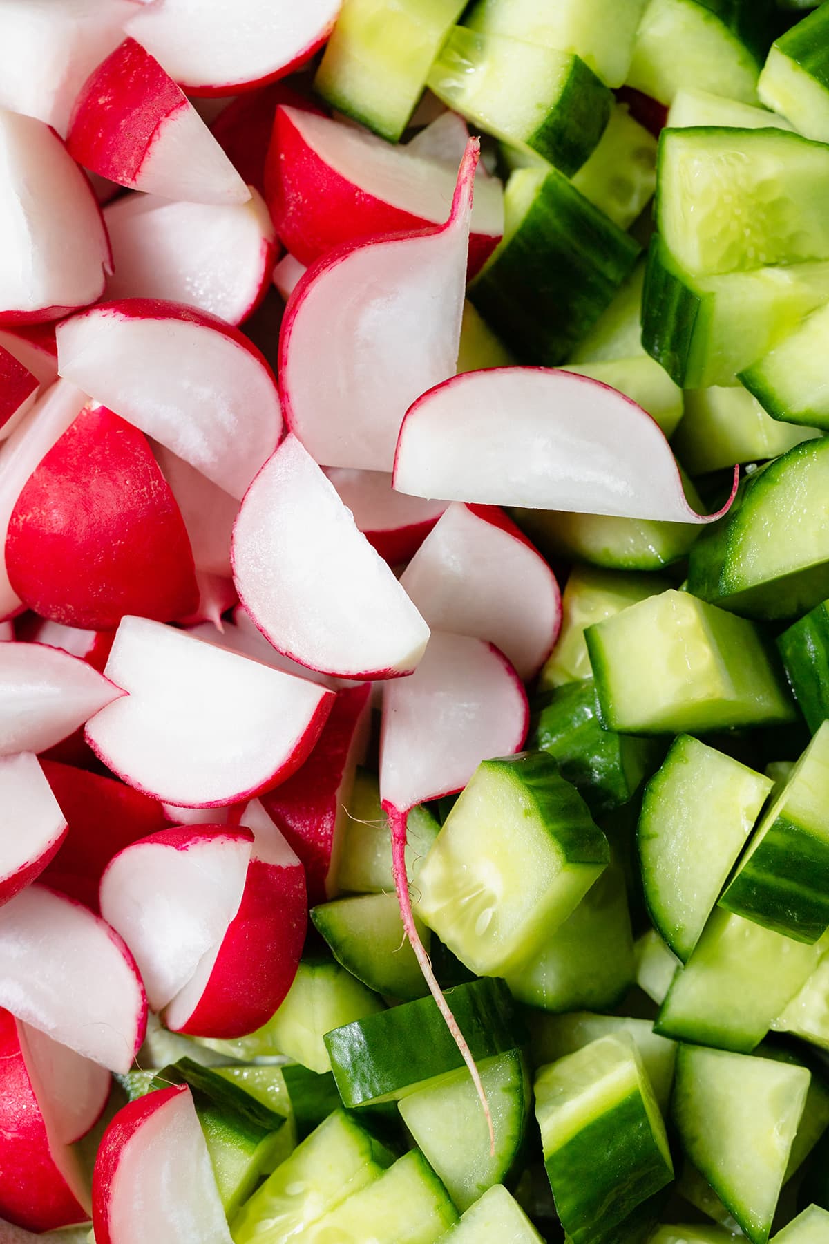 A close up of chopped radishes and cucumber.