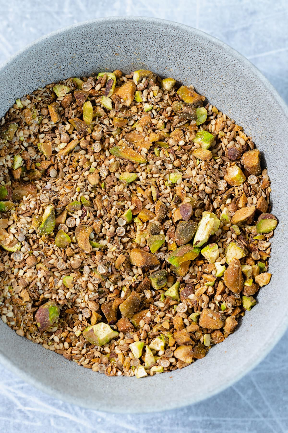 Pistachio dukkah in a grey bowl. Shot from above, a close up.