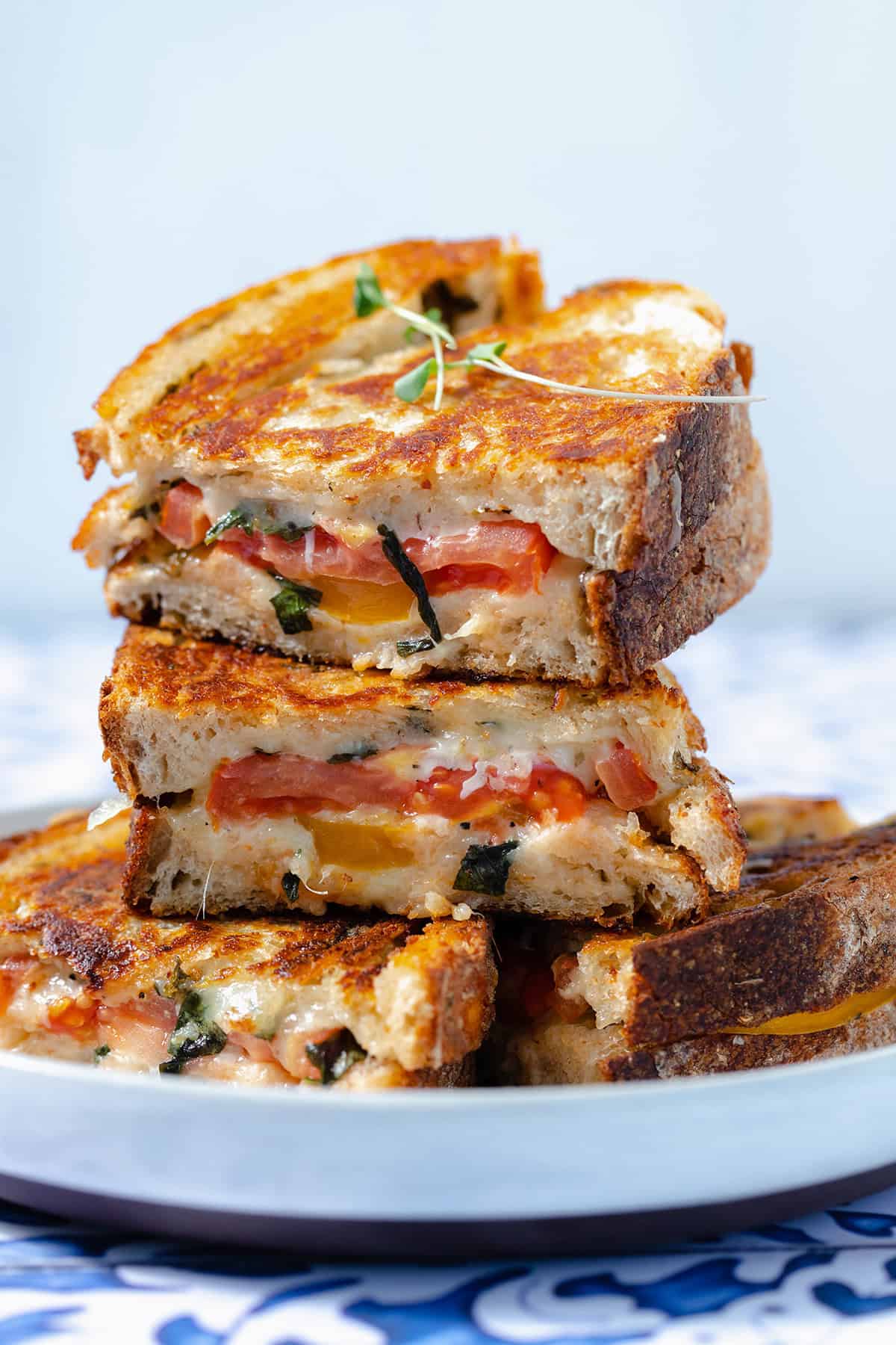 A close up of four tomato grilled cheese sandwiches stacked on top of each other.