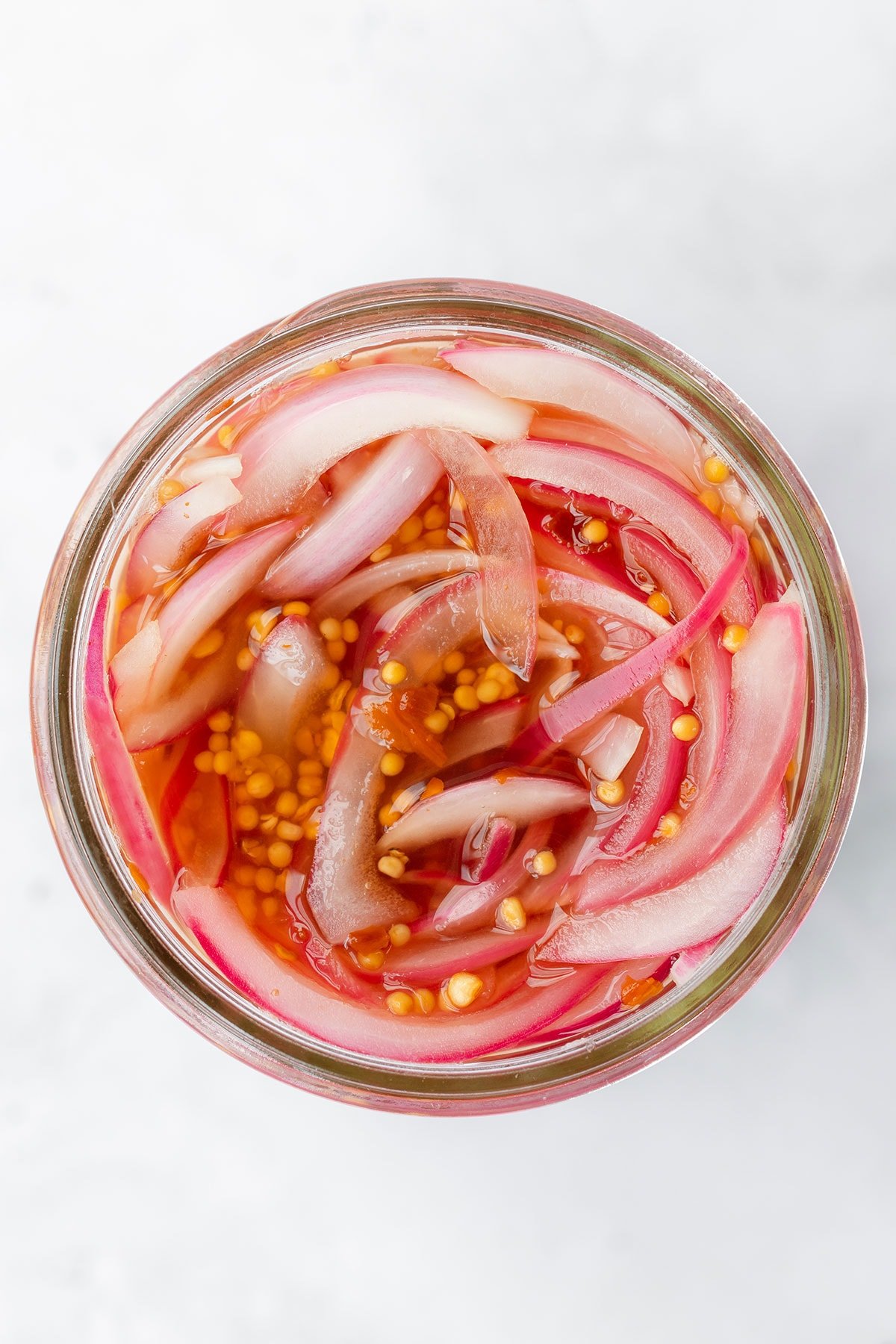 Pickled red onions in a jar slightly wilted after 30 minutes of pickling.