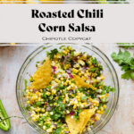 Corn salsa in a glass bowl with tortilla chips dipped in. There are more tortilla chips, fresh cilantro, corn, and jalapenos around. All on a light wooden background. The text in photo says "Roasted chili Corn Salsa Chipotle Copycat".