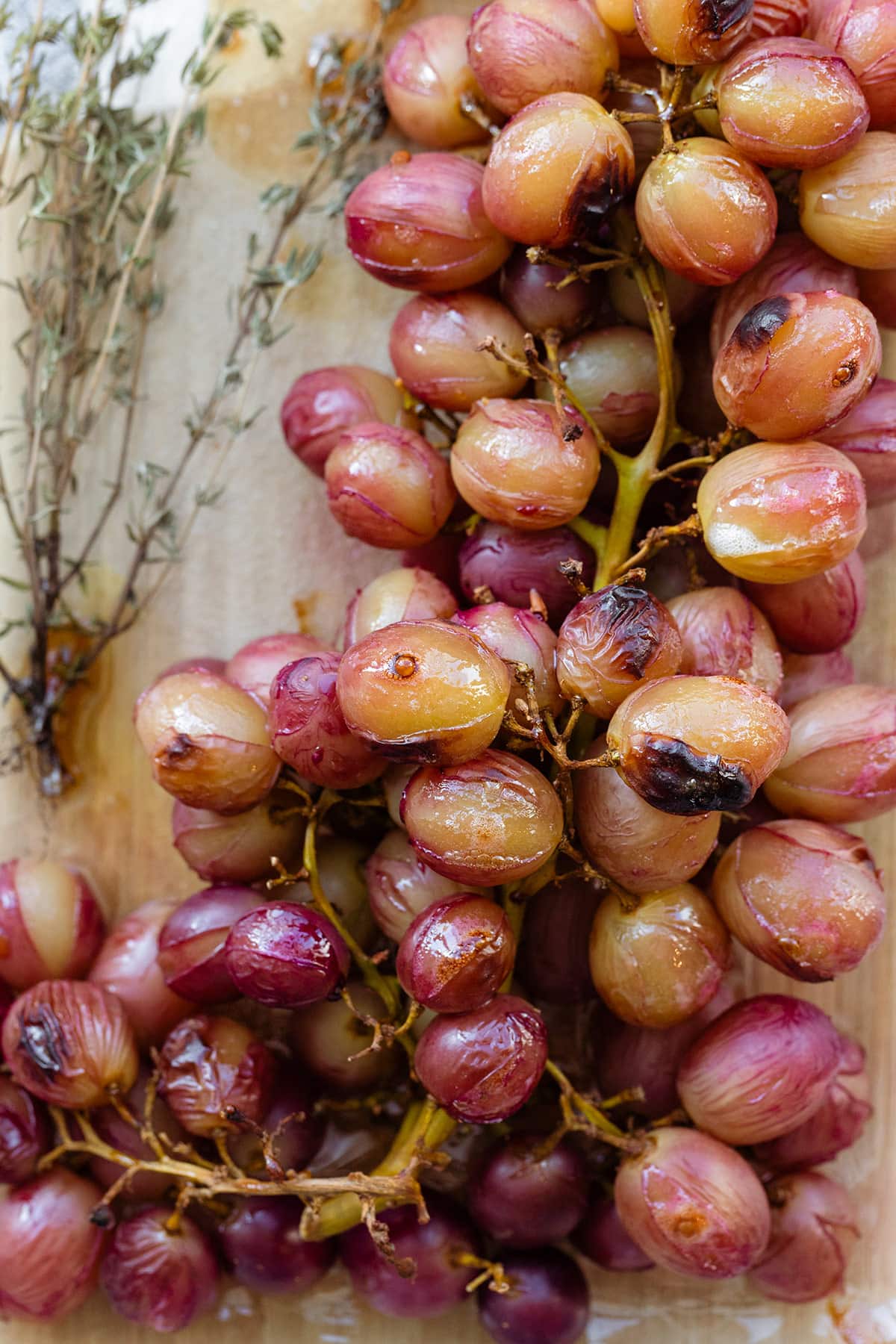 Roasted grapes on a wine on a wooden cutting board.