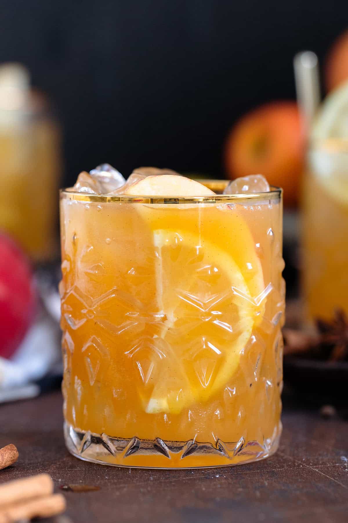 Bourbon cocktail in a glass with a gold rim on a dark wooden background.