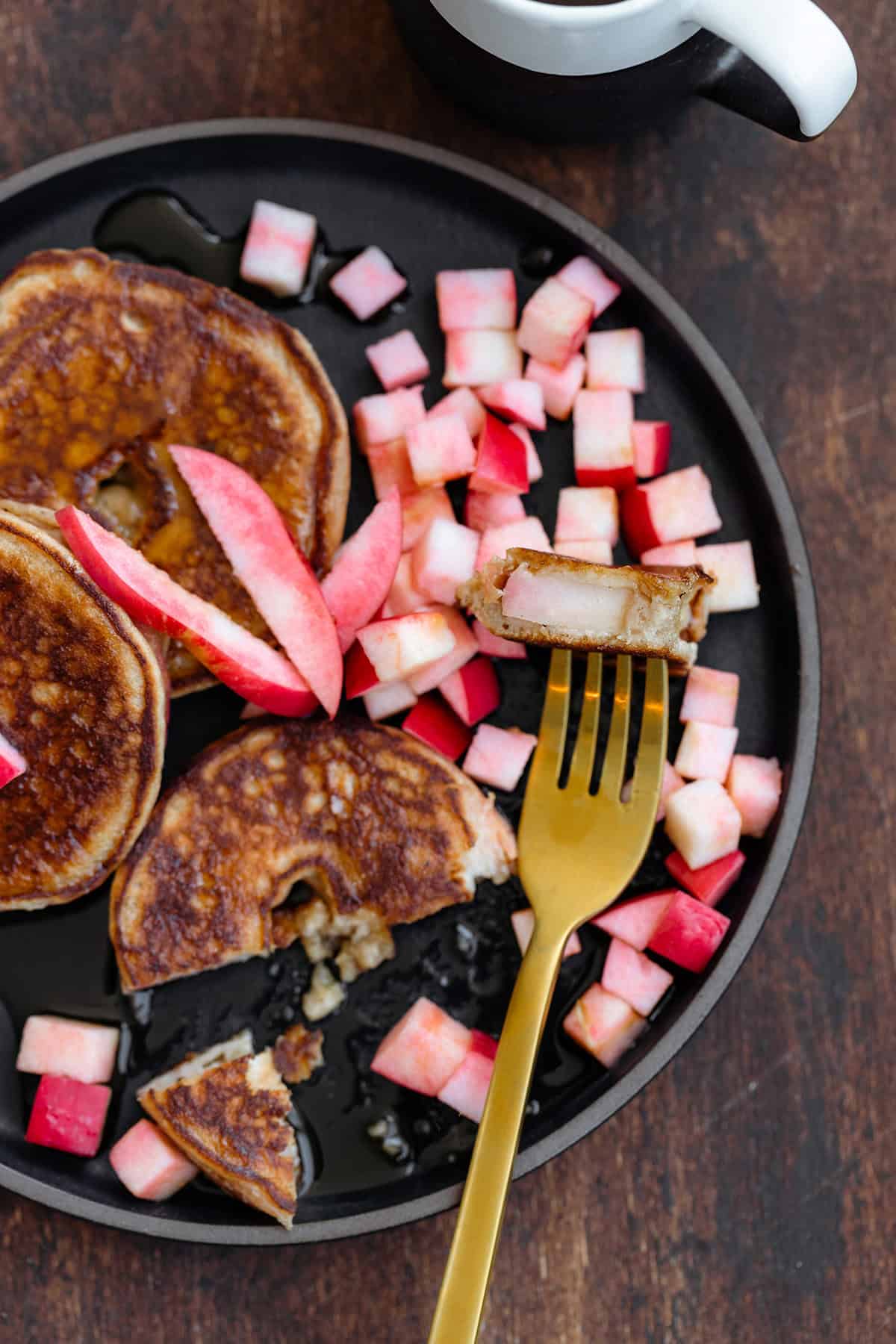 Apple ring pancakes with diced apples and a gold fork topped with diced apples.