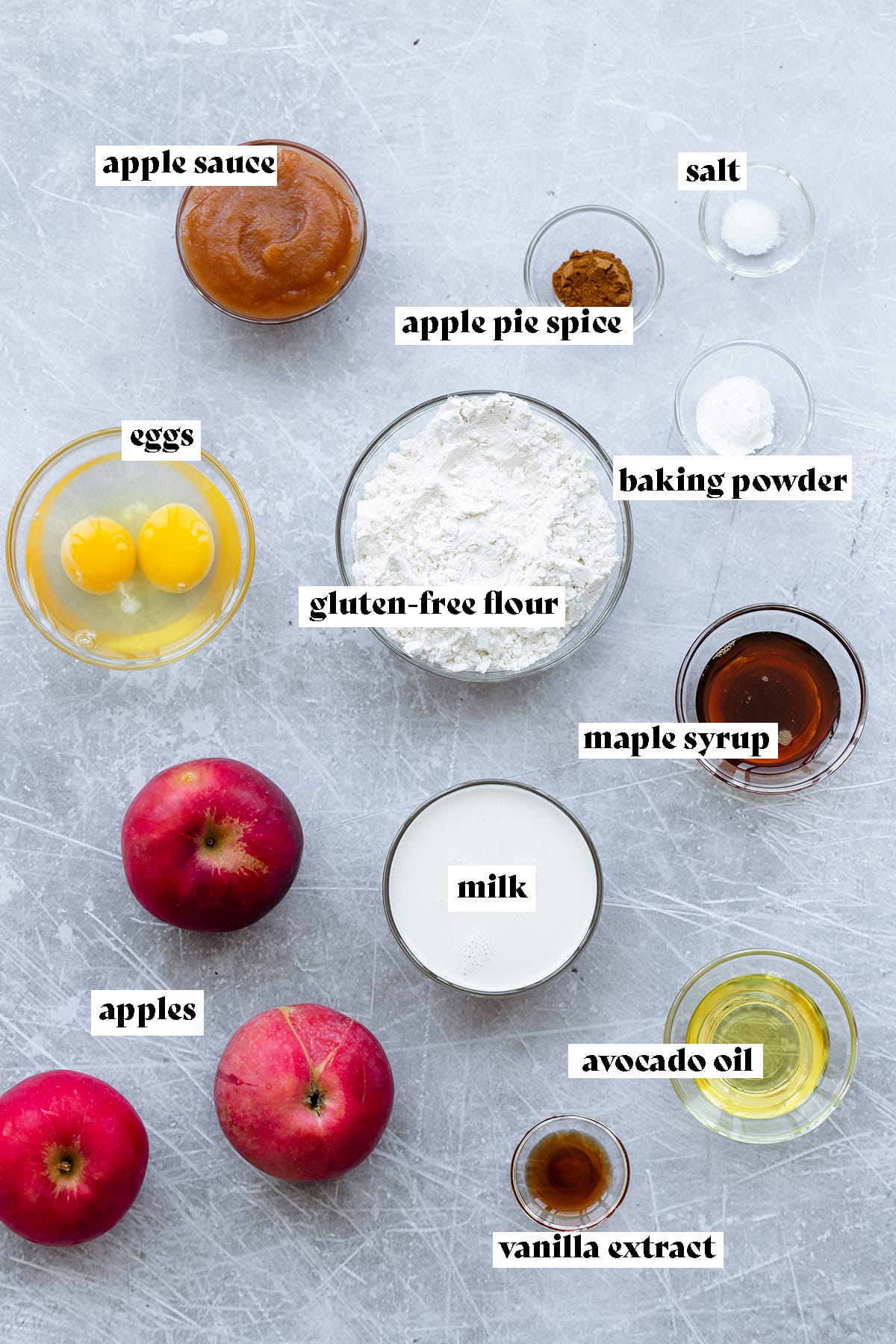 Ingredients for apple ring pancakes all laid out on a light metal background.