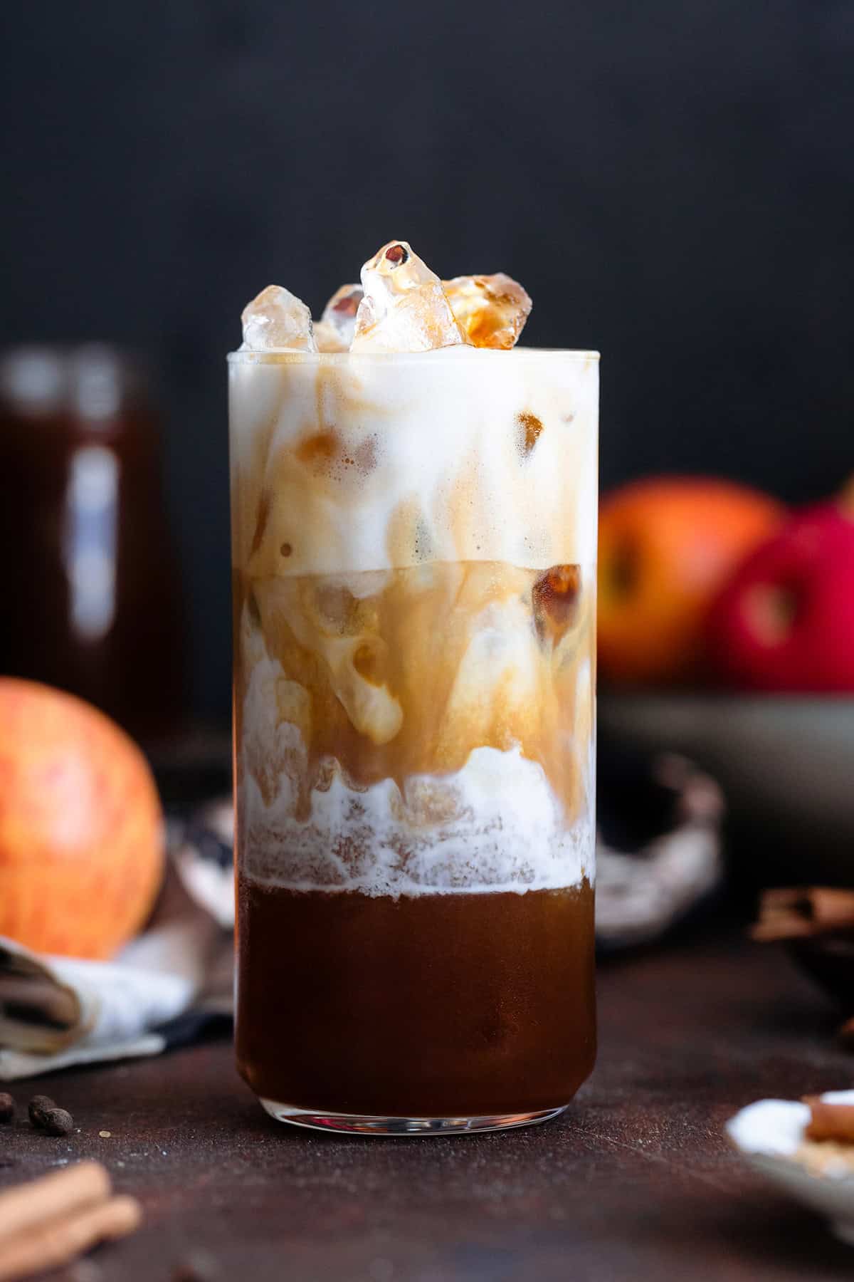 Espresso slowly mixing with frothy milk in a tall glass filled with ice.