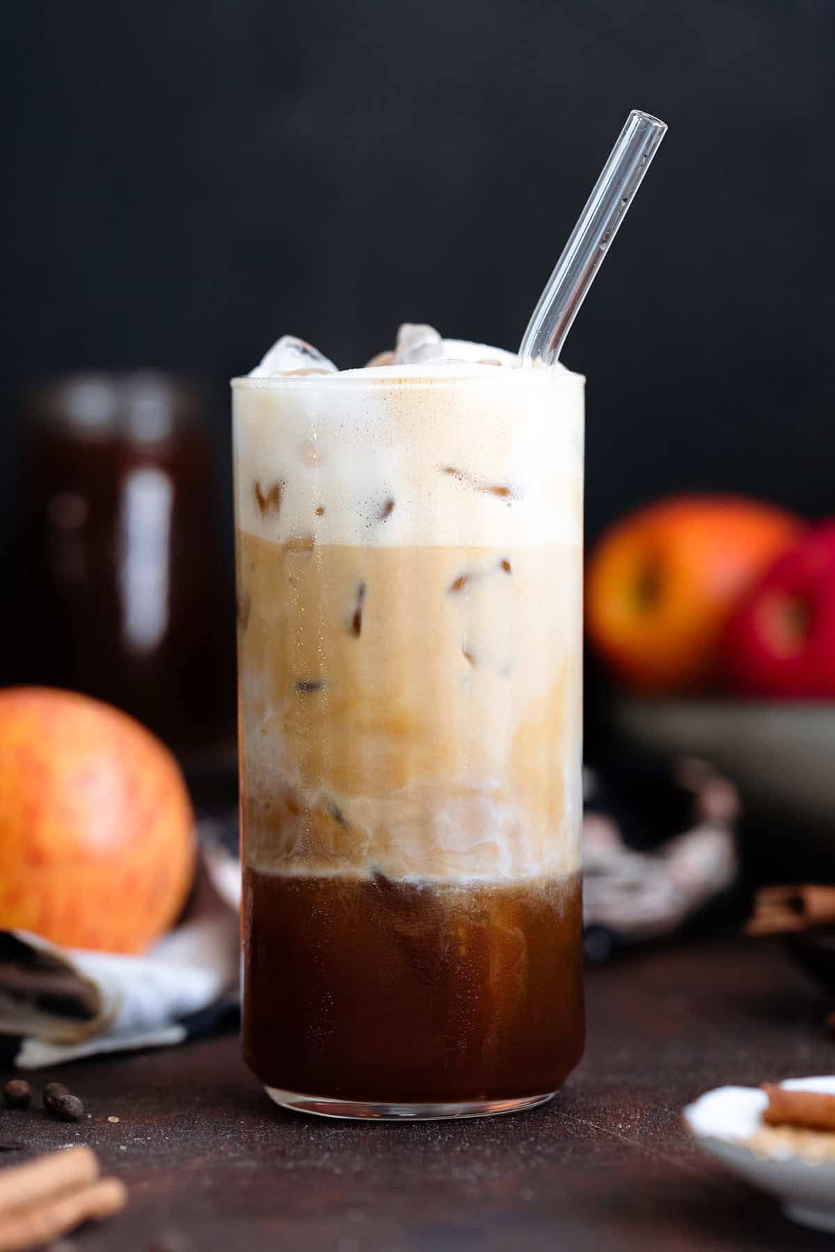 Espresso slowly mixing with frothy milk in a tall glass filled with ice.