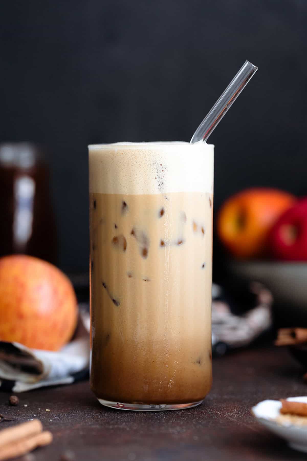 A tall glass with an iced macchiato on a dark background.