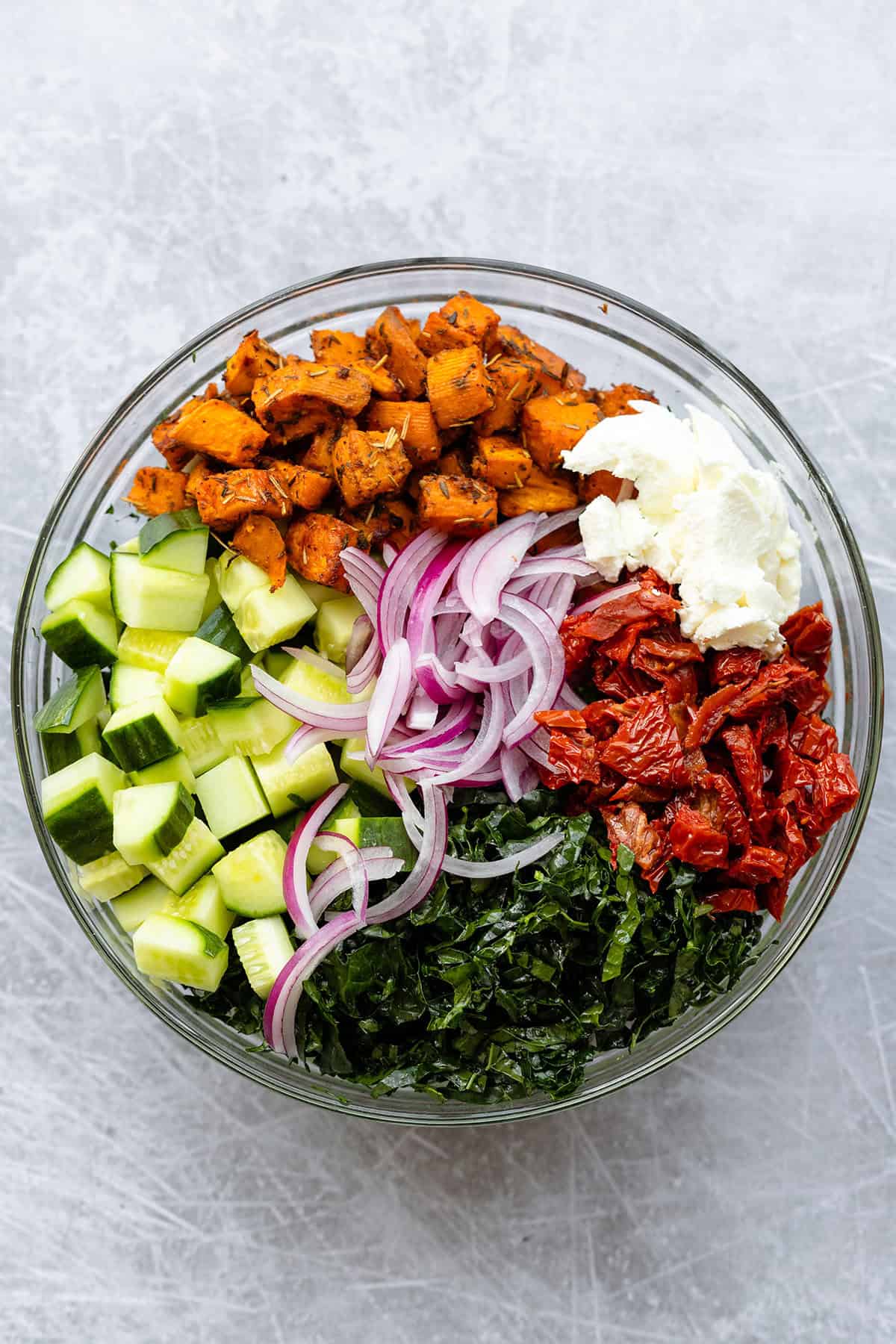 Ingredients for kale salad all chopped in a glass bowl.