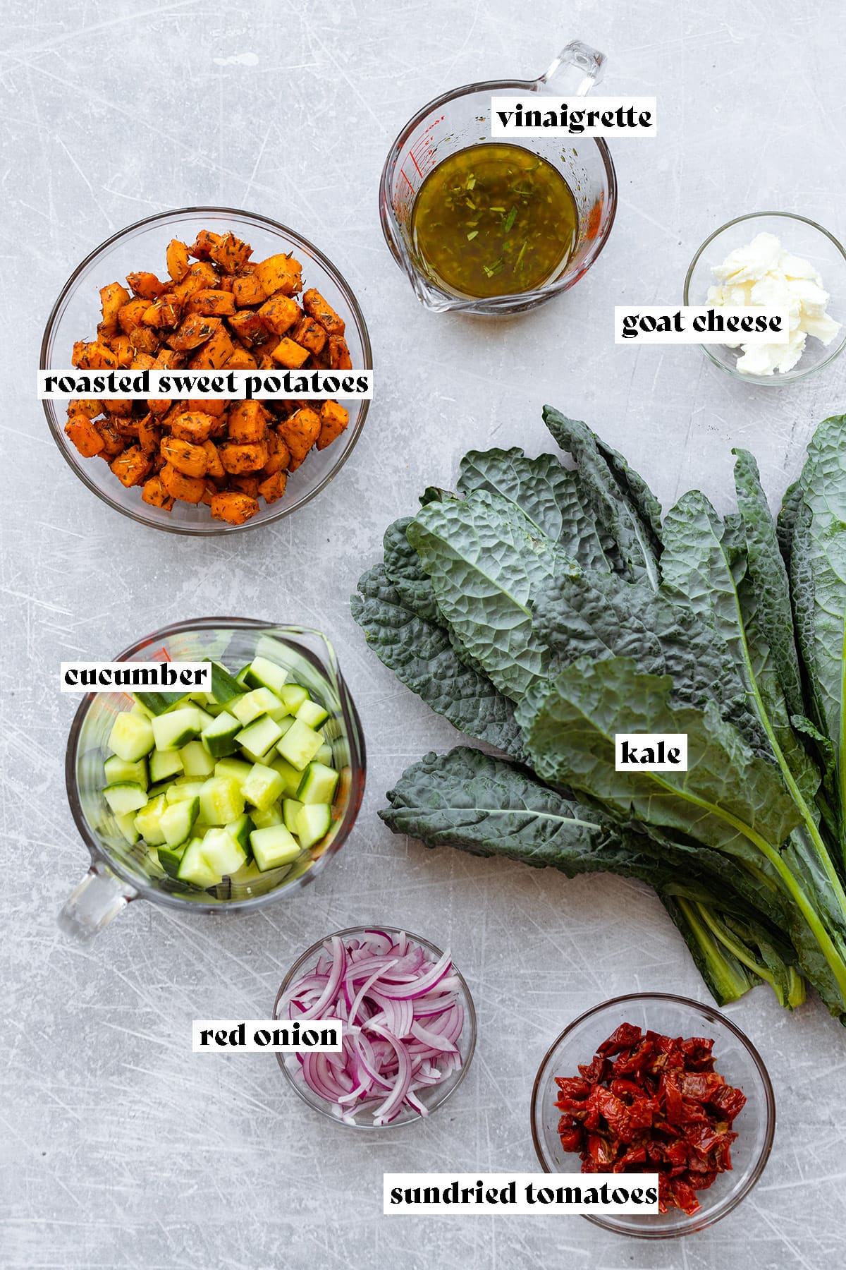 Ingredients for kale salad laid out on a light metal background.