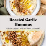 Hummus in a shallow grey bowl topped with pine nuts, roasted garlic, and olive oil.