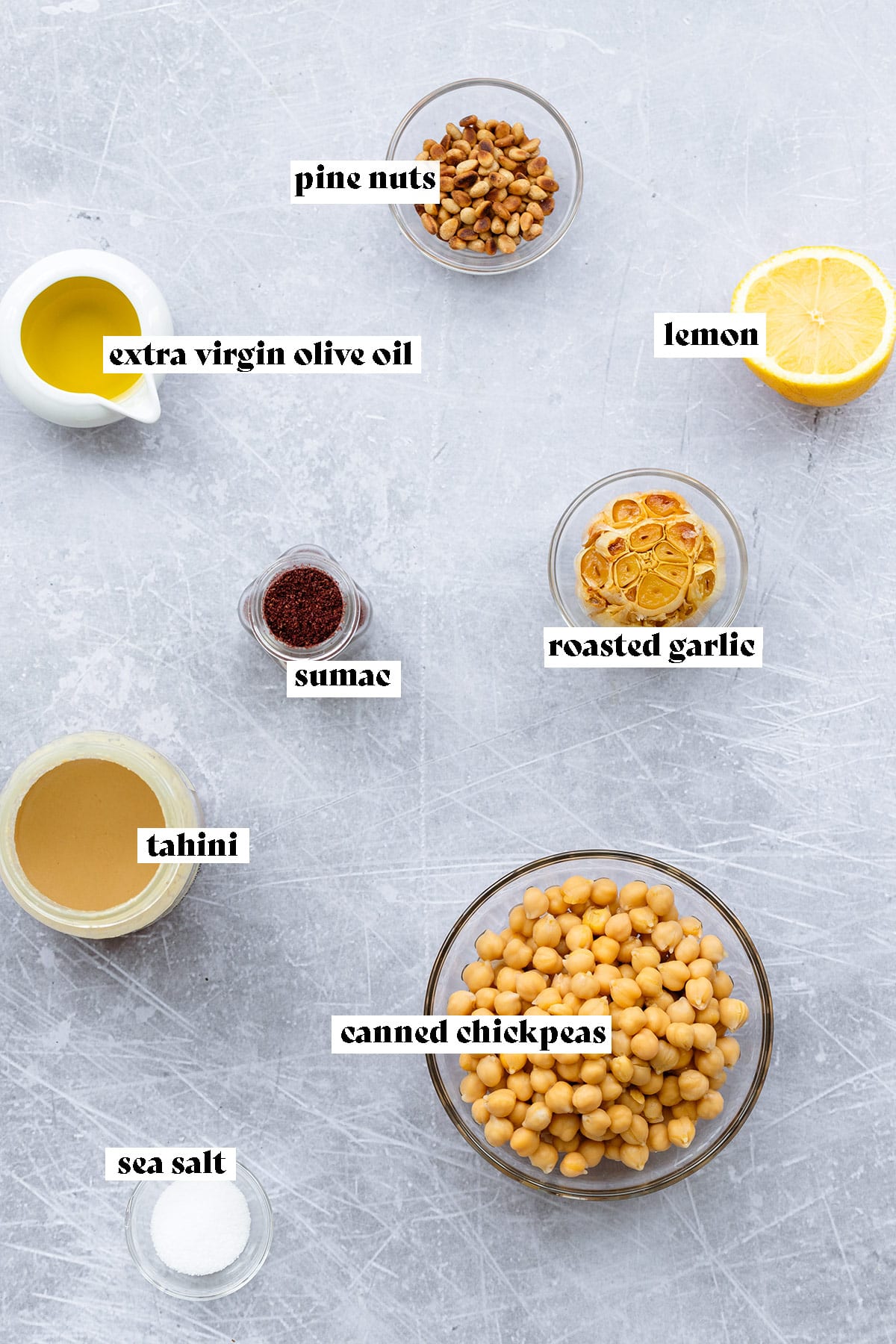 Ingredients for roasted garlic hummus laid out on a light metal background.