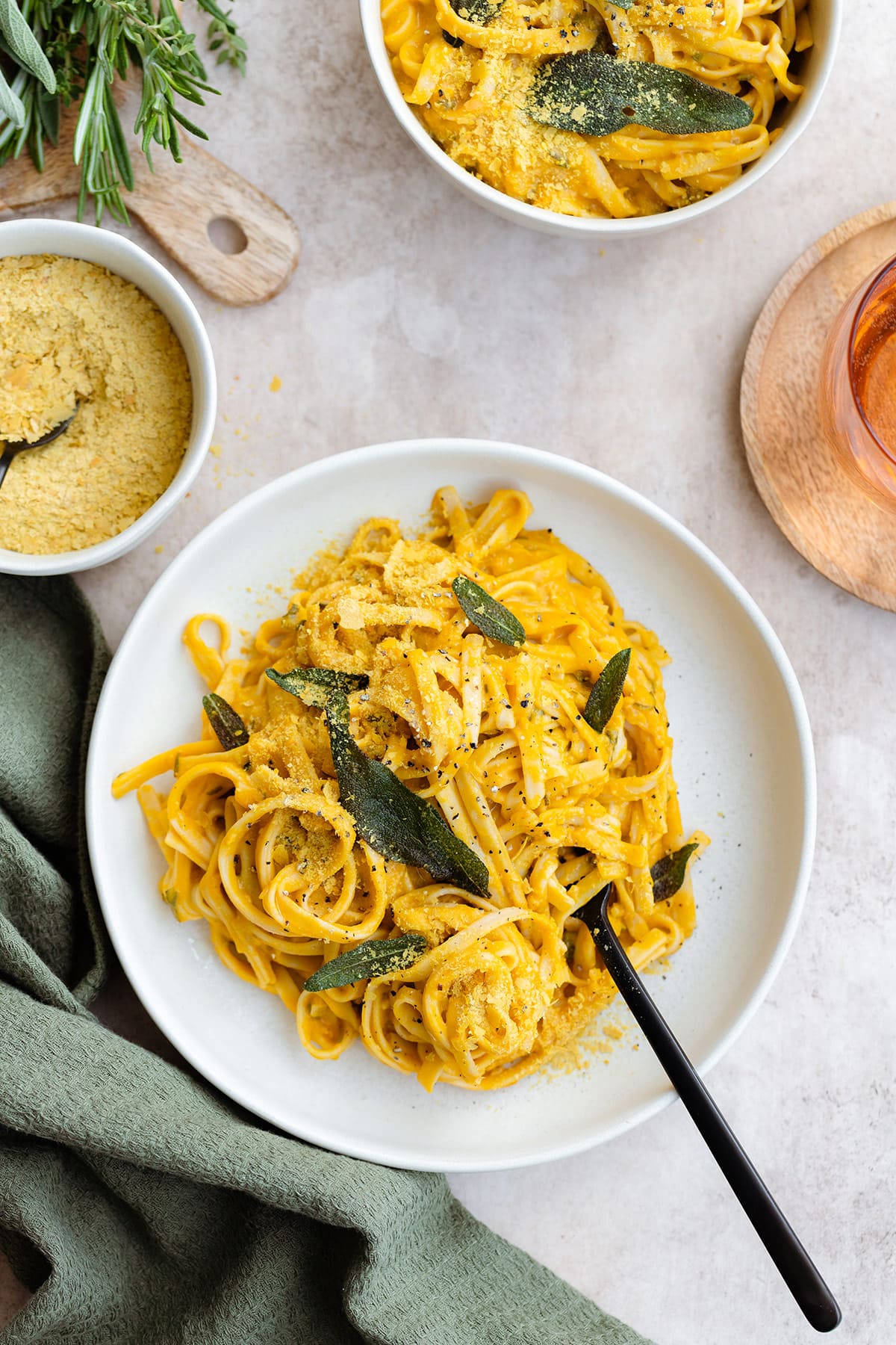 Pumpkin pasta topped with sage and nutritional yeast on a white plate.