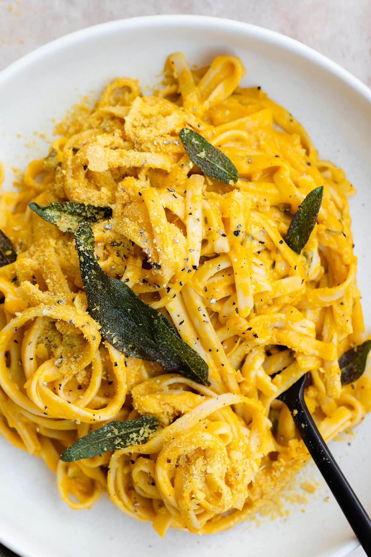 A close up of pumpkin pasta topped with fried sage leaves.