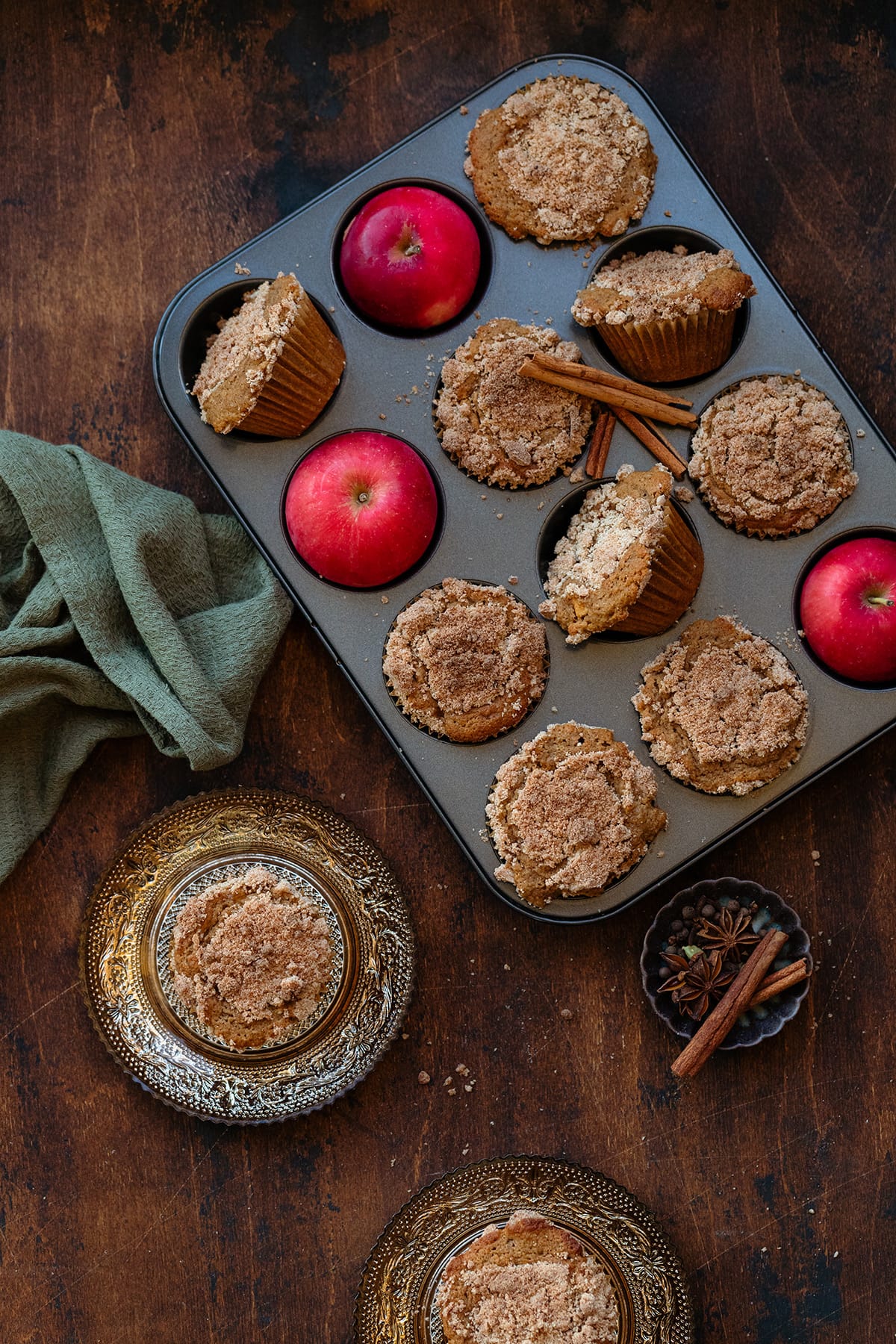 Apple muffins in a muffin pan on a wooden background.