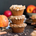 Apple muffins stacked on a wooden background.