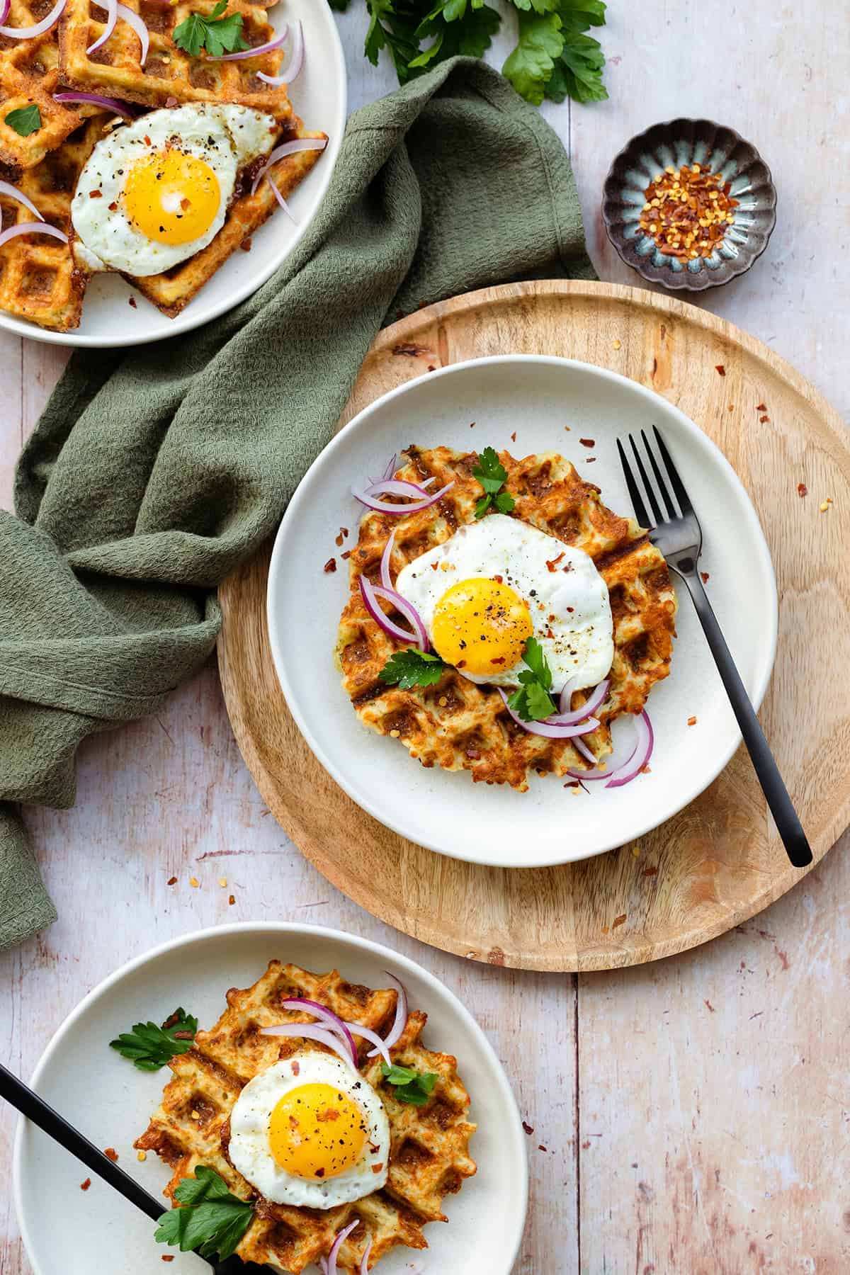 Waffles on a white plate with a sunny side up egg on top and red onions.