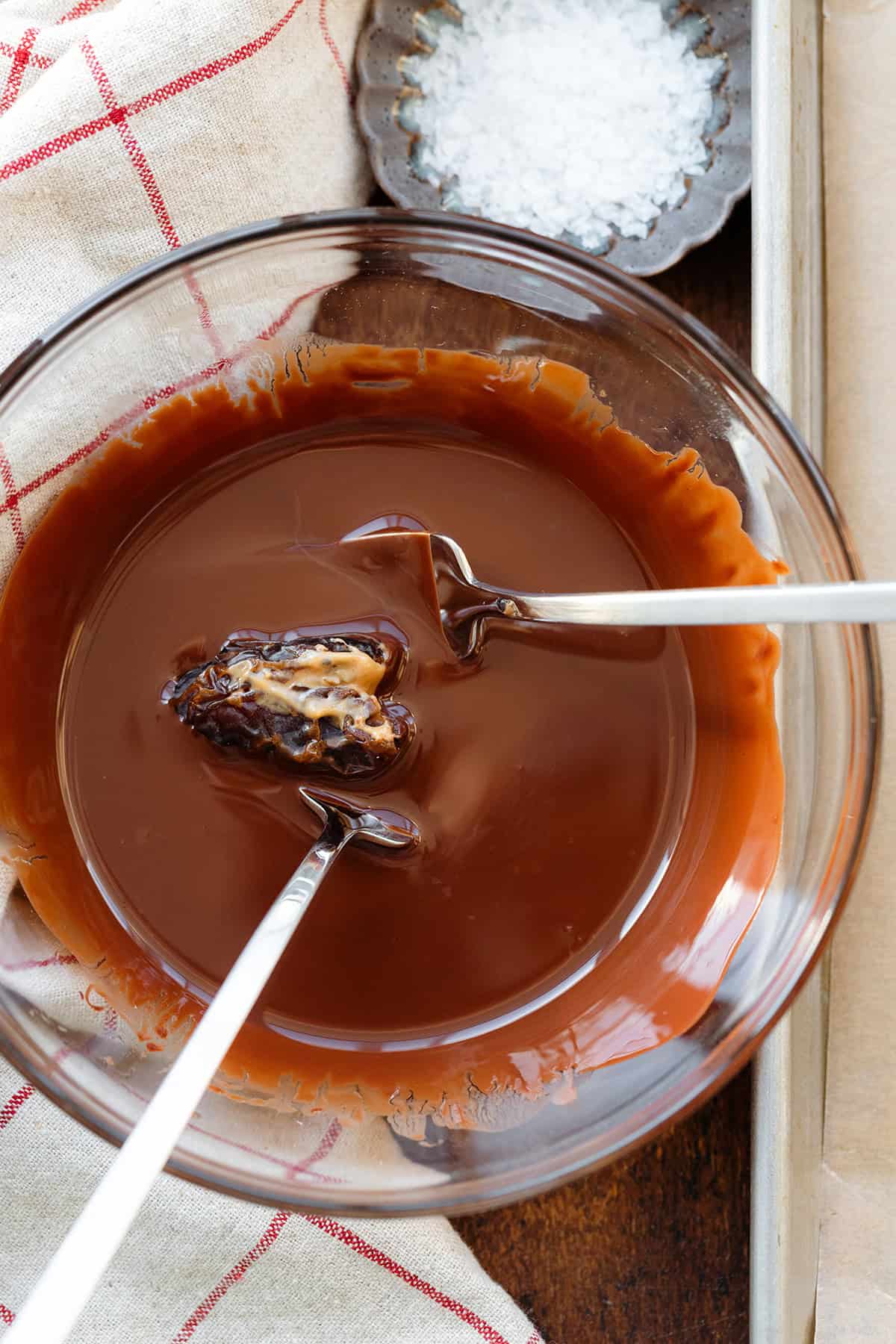 A nut butter stuffed medjool date dipped into a bowl of melted chocolate.