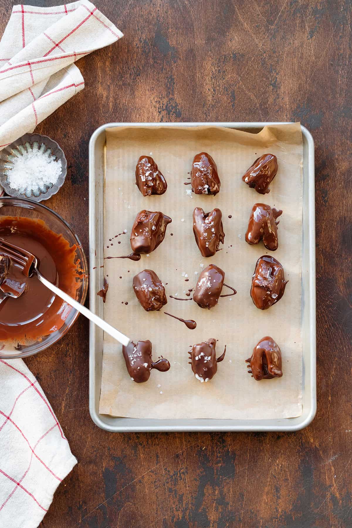 Chocolate covered dates sprinkled with sea salt on a baking sheet.