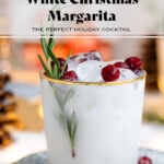 White margarita in a short glass with a gold rim, garnished with fresh cranberries, and rosemary spring.