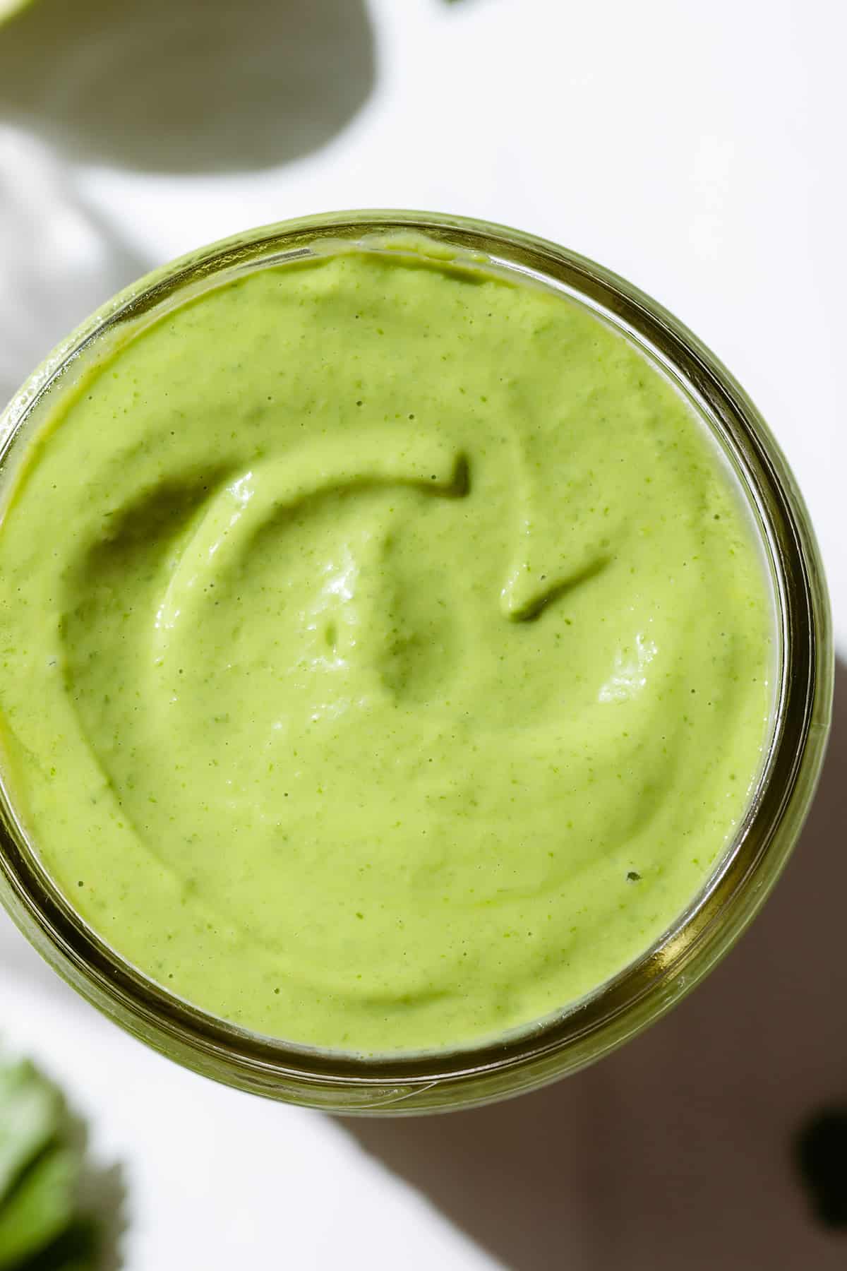 A close up shot of green goddess dressing in a mason jar shot from above.