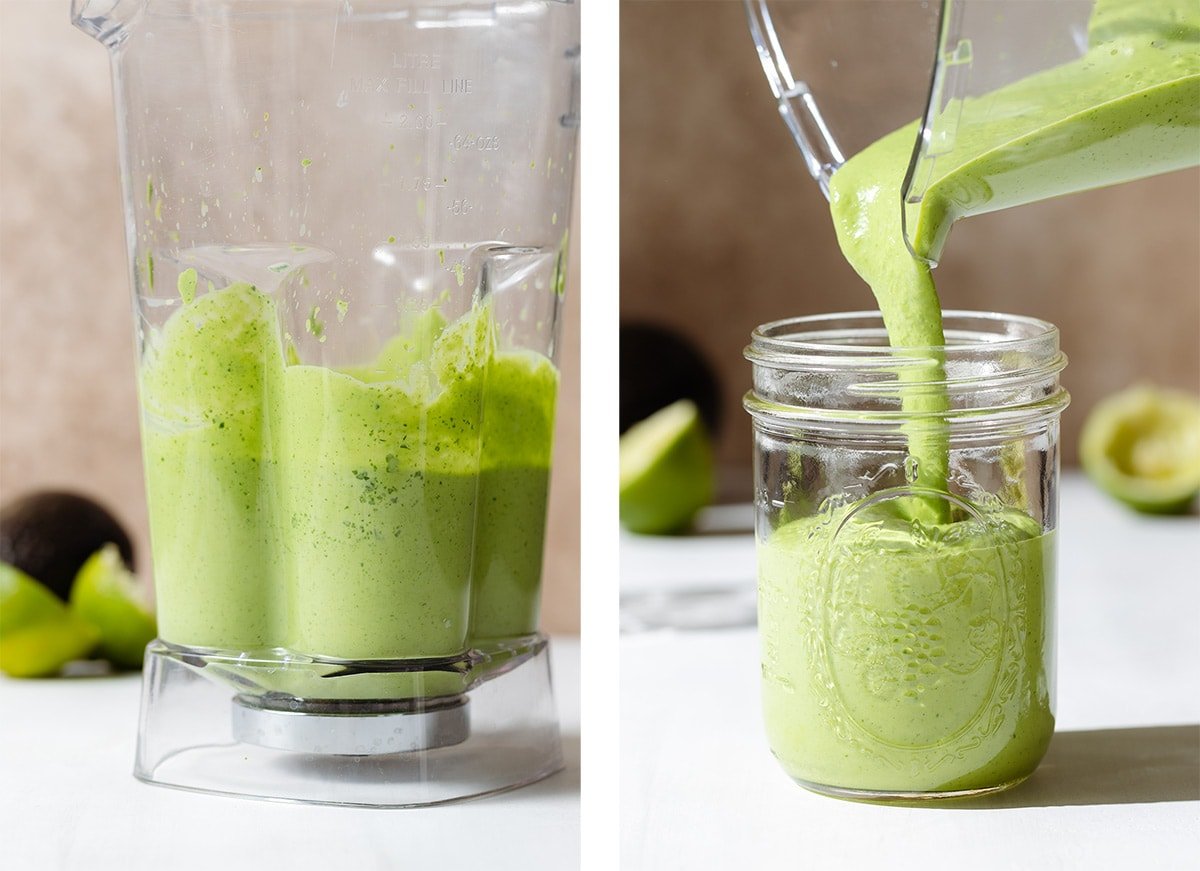 Thick green dressing being poured into a mason jar from a blender jar on a white background.