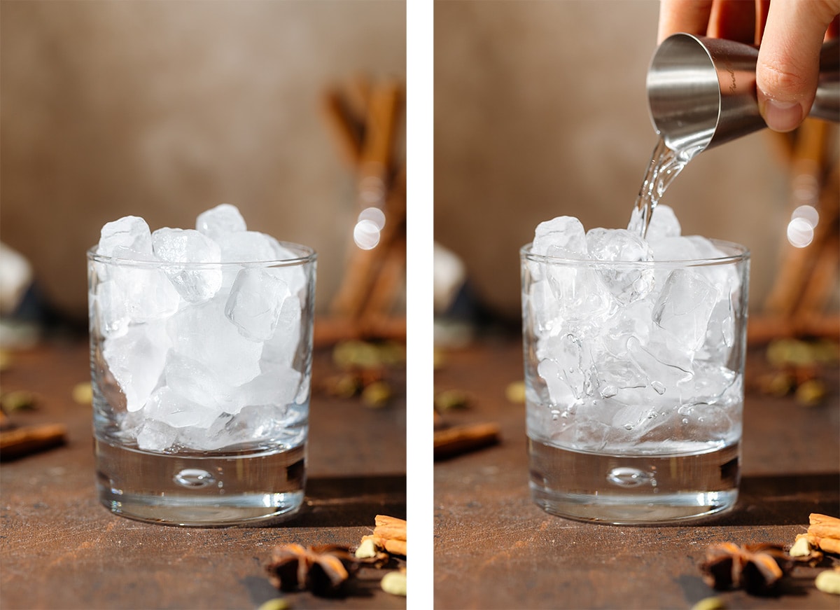 A hand pouring vodka into a short glass filled with ice.