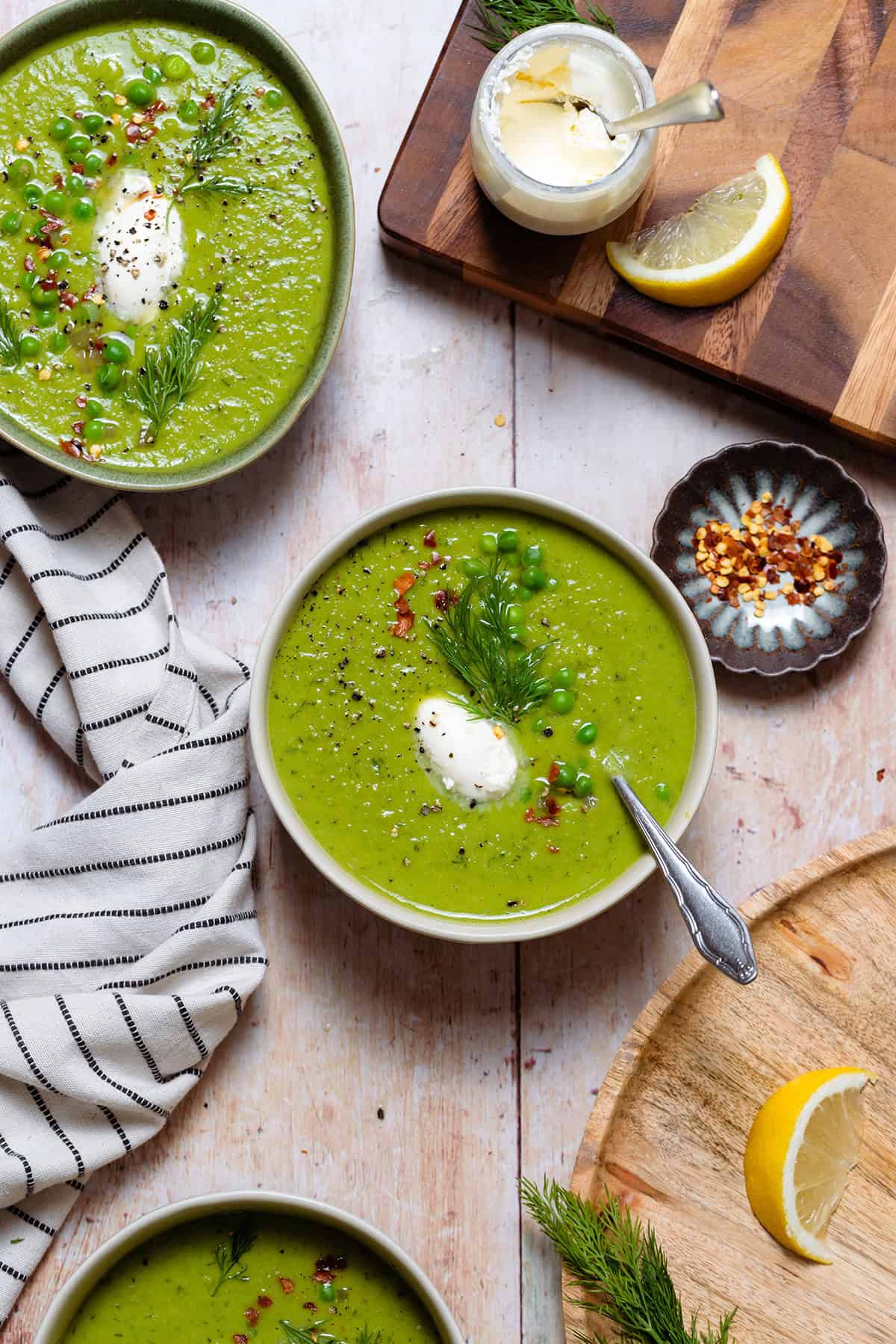 Green soup in white bowls on a light wooden background.