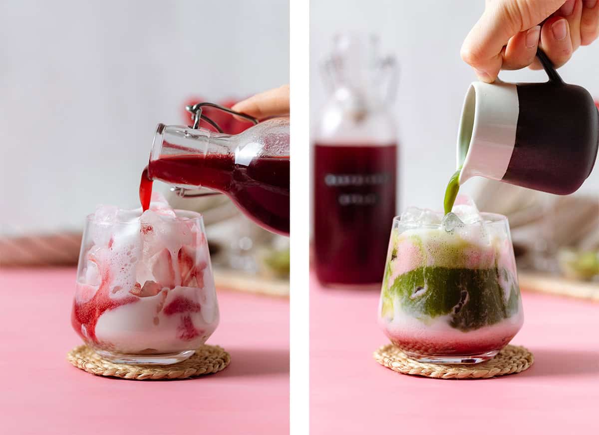 Raspberry syrup and matcha being poured into a glass with almond milk on a pink background.