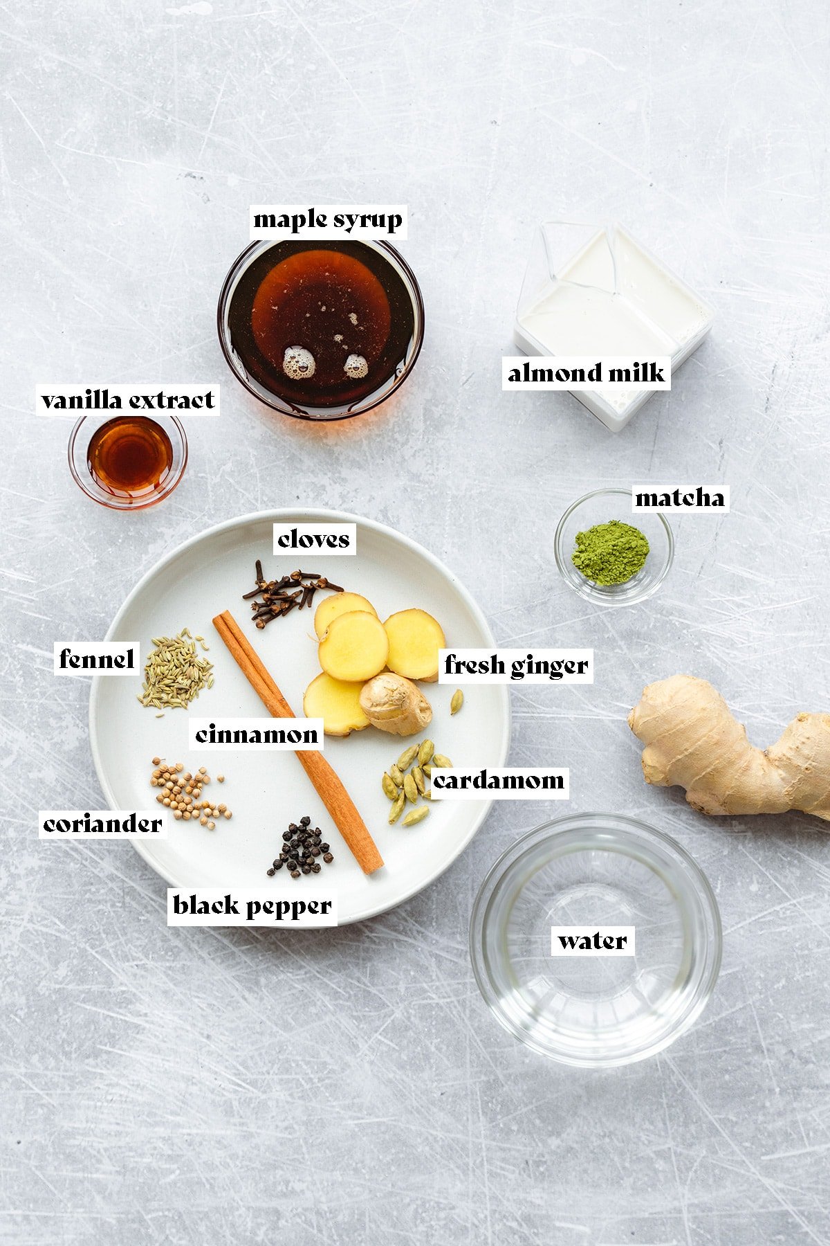 Ingredients for matcha latte and chai syrup laid out on a metal background.