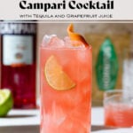 Light red colored campari cocktail in a tall glass with ice and a lime slice.