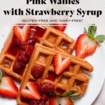 Waffles with syrup and fresh strawberries on a white plate on a stone background.