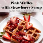 Waffles with strawberry syrup and fresh strawberries on a white plate on a stone background.