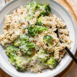 A close up of broccoli pasta with grated cheese and chili flakes.