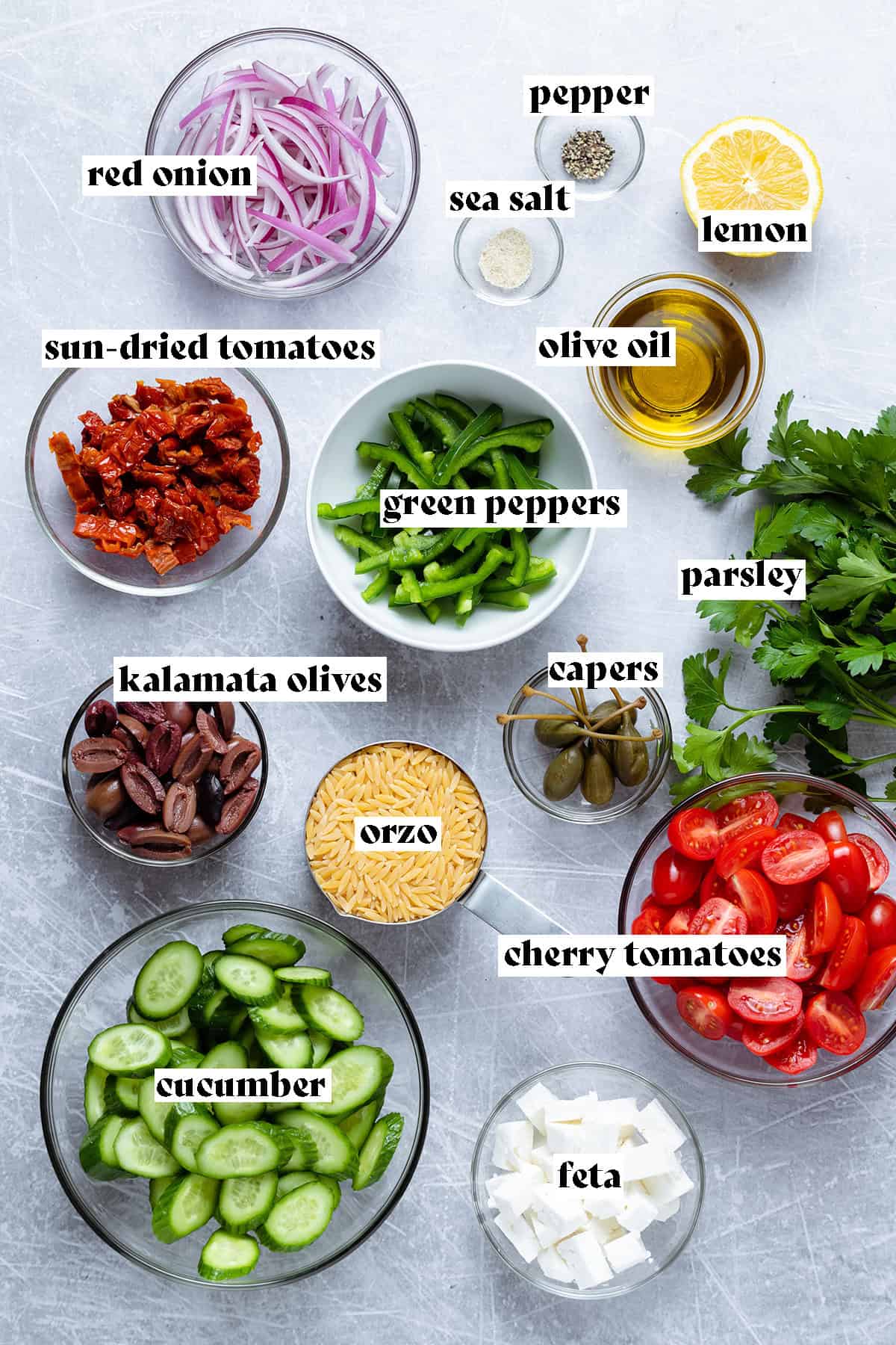 Various vegetables and orzo for a Green Orzo Salad laid out on a metal background.