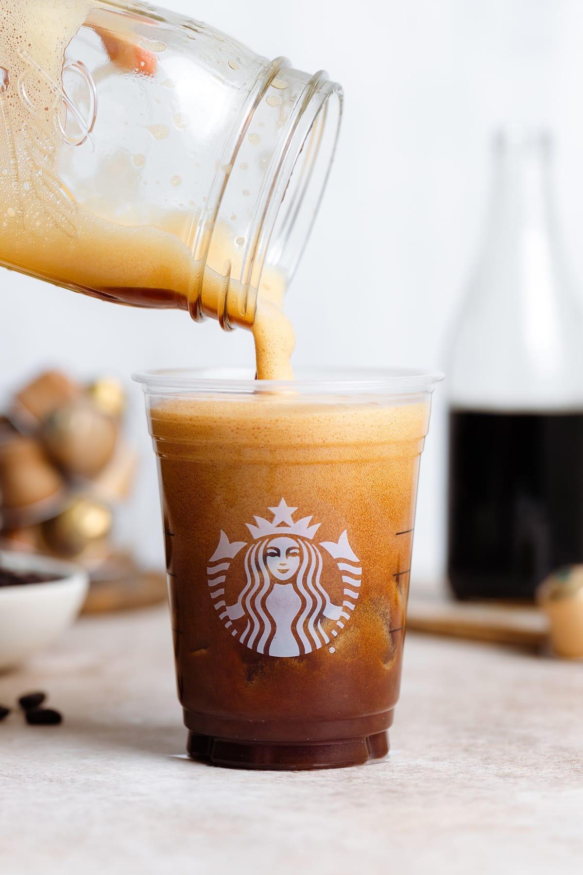 Espresso shaken with ice being poured into a Starbucks cup from a mason jar.