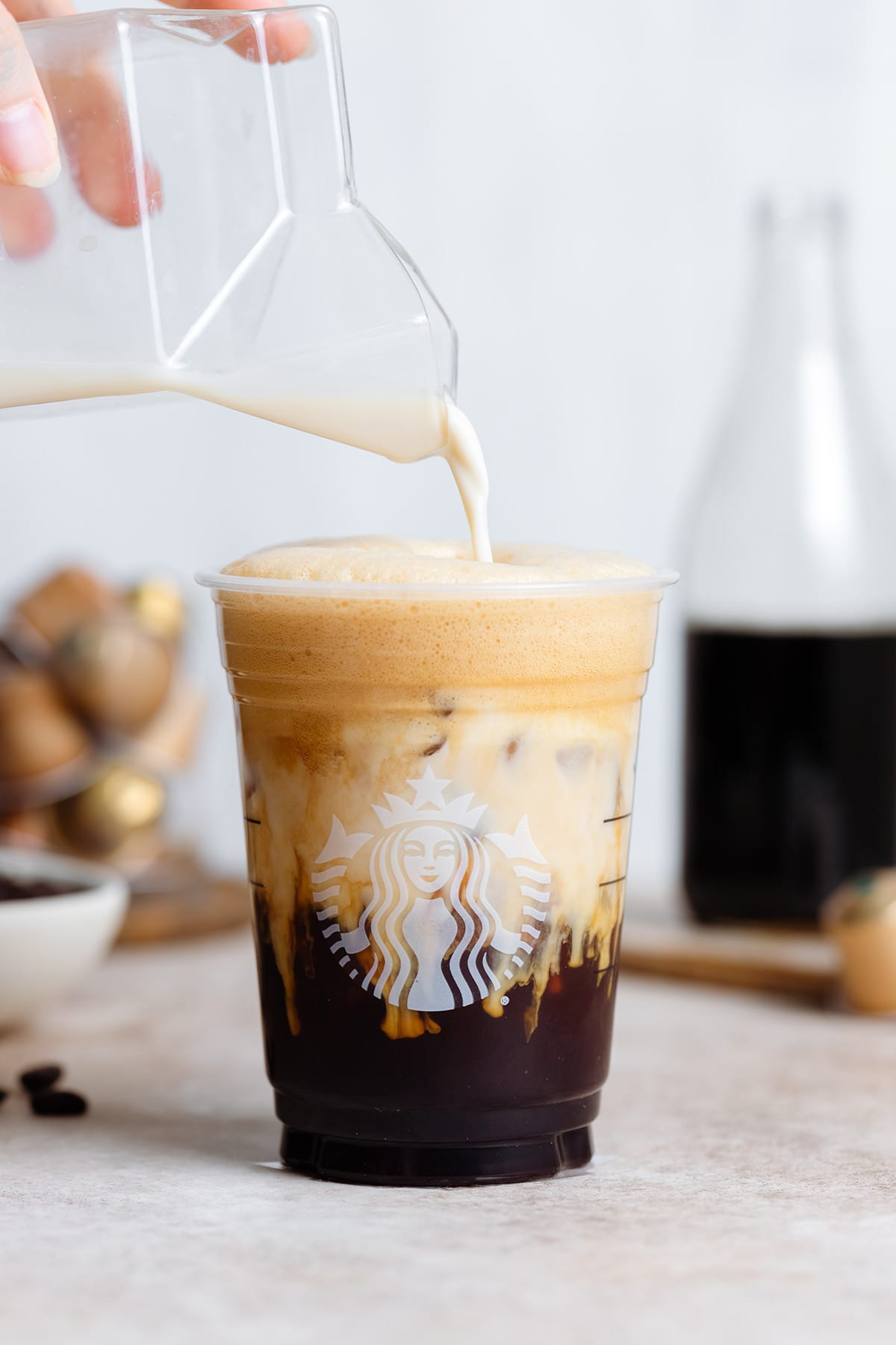 Milk being poured into a Starbucks cup with iced shaken espresso.