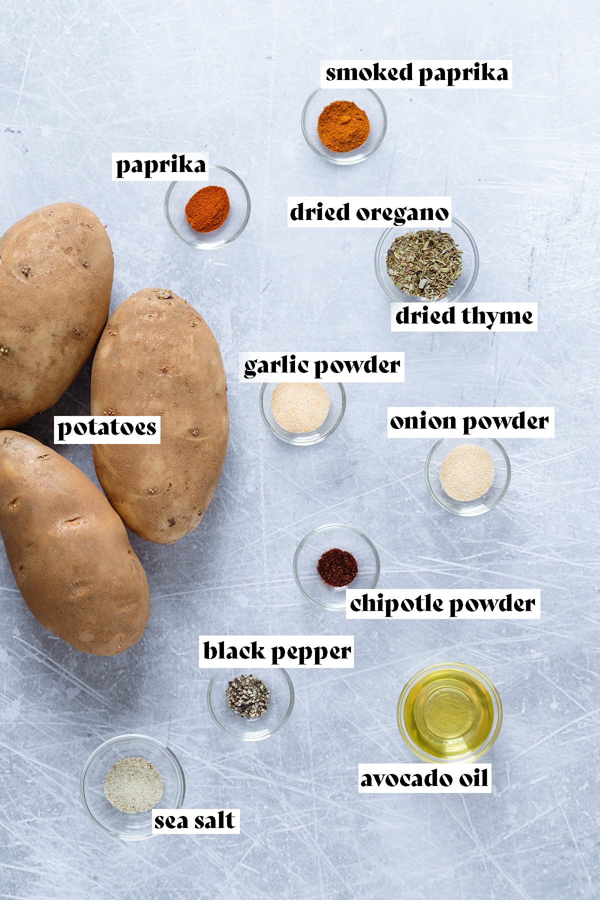 Potatoes and spices all laid out on a metal background.