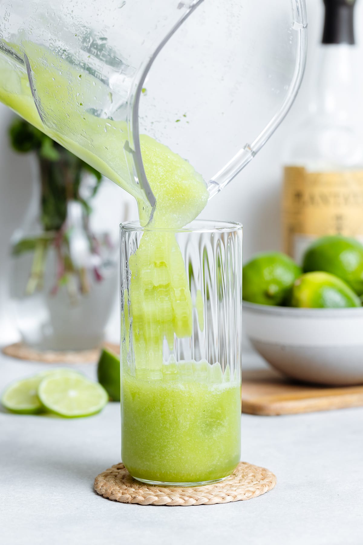 Blended frozen mojito being pored into a tall glass.