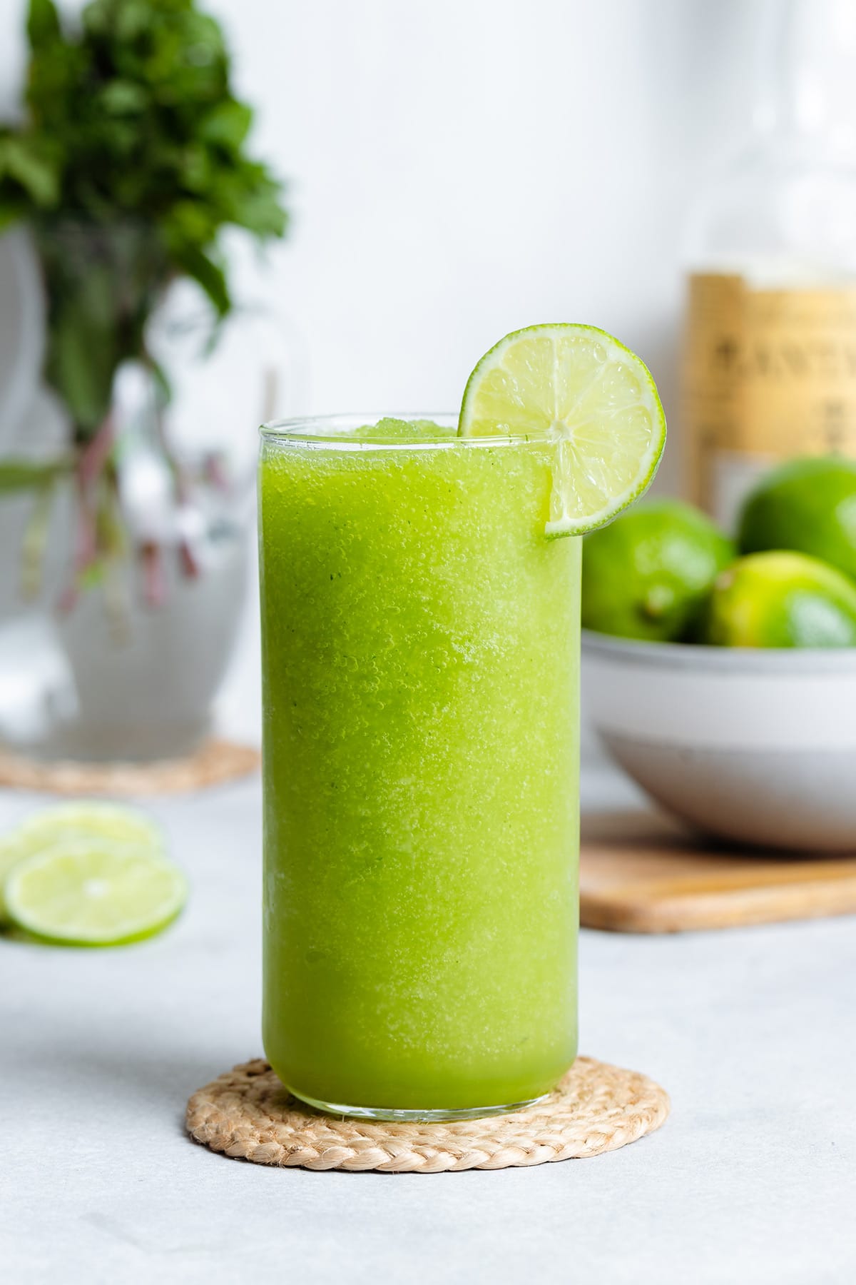 Blended mojito in a tall glass garnished with a slice of lime.